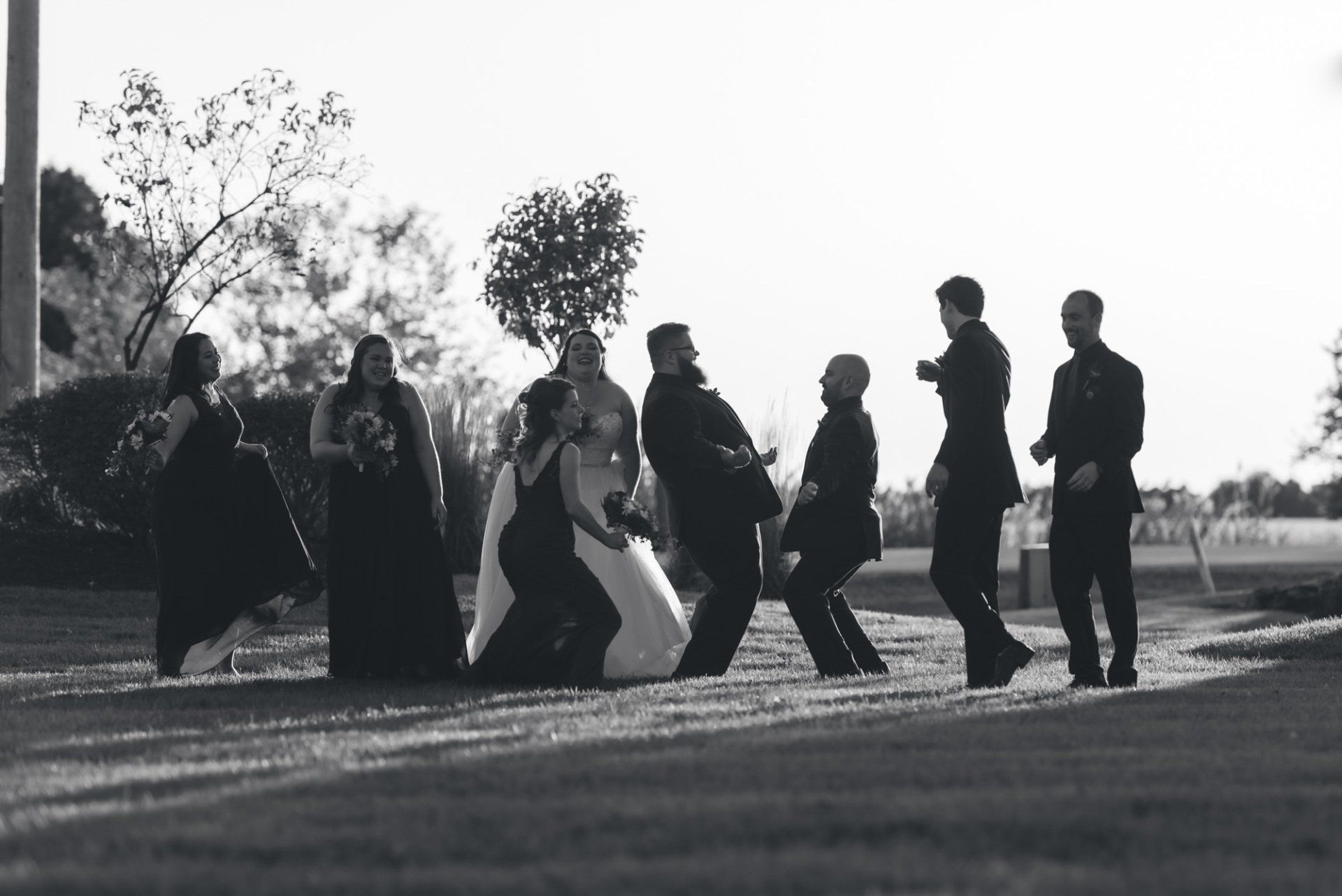 A bride and groom are walking with their wedding party in a black and white photo.