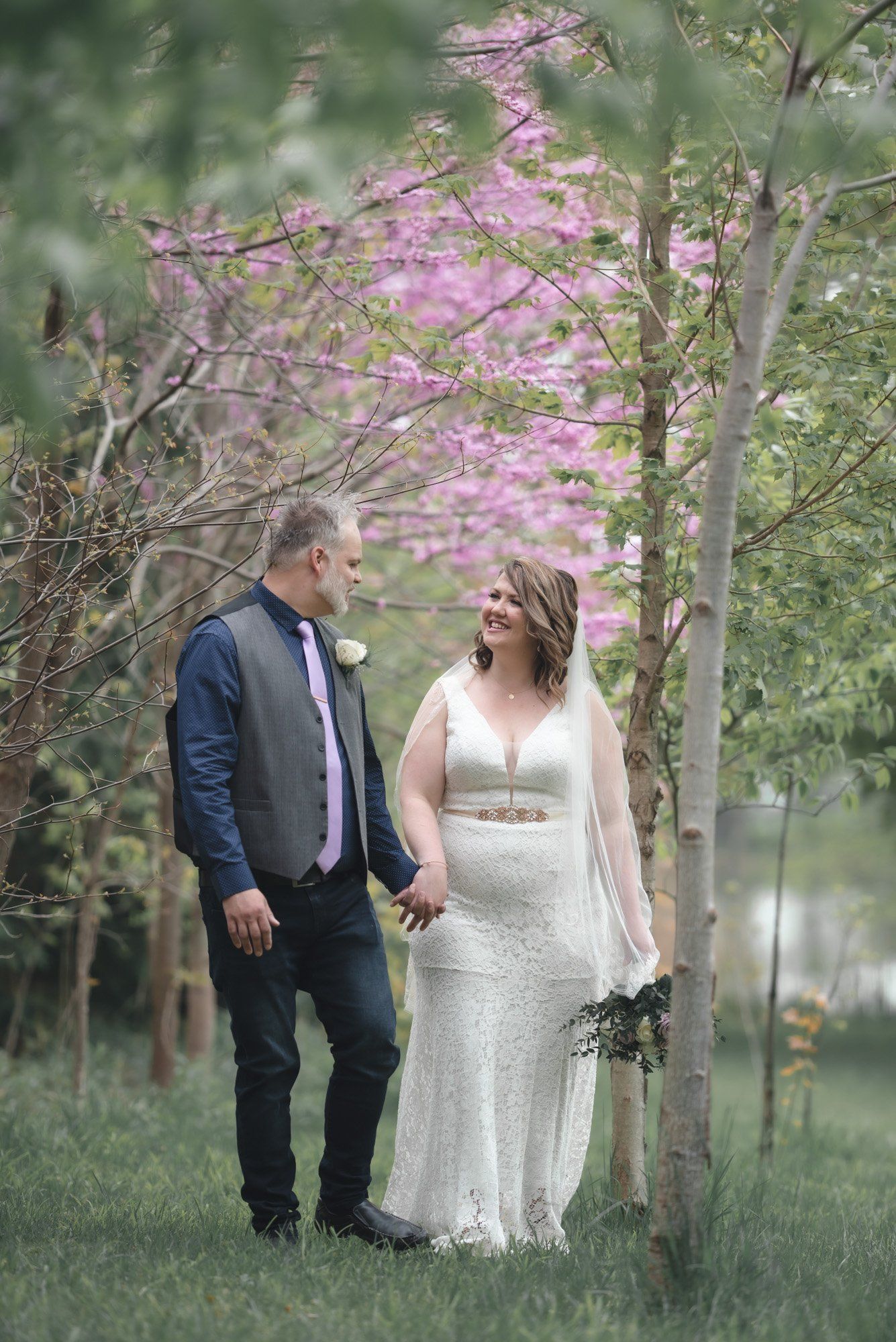 A bride and groom are holding hands in a park.