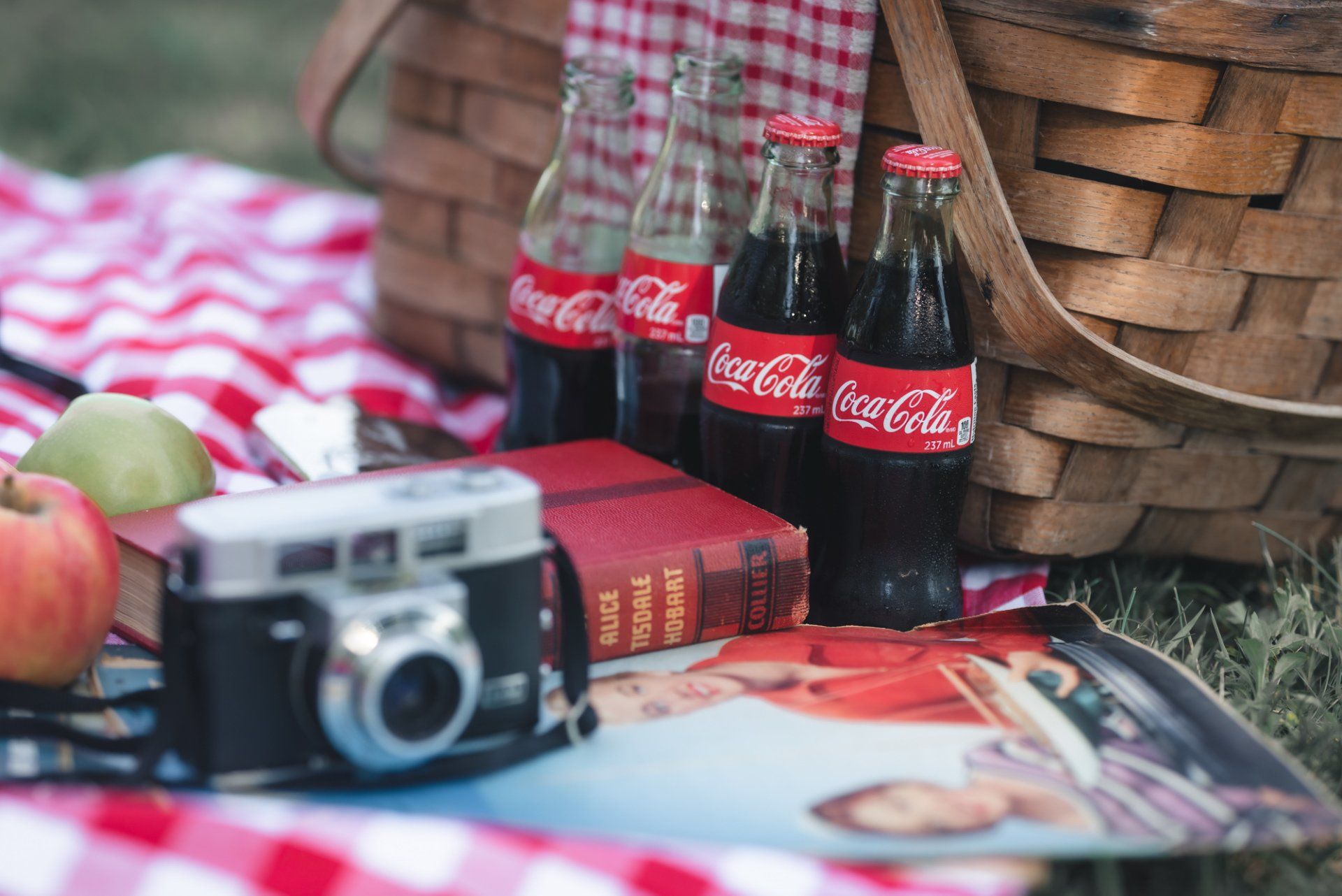 A picnic basket filled with coca cola bottles and apples