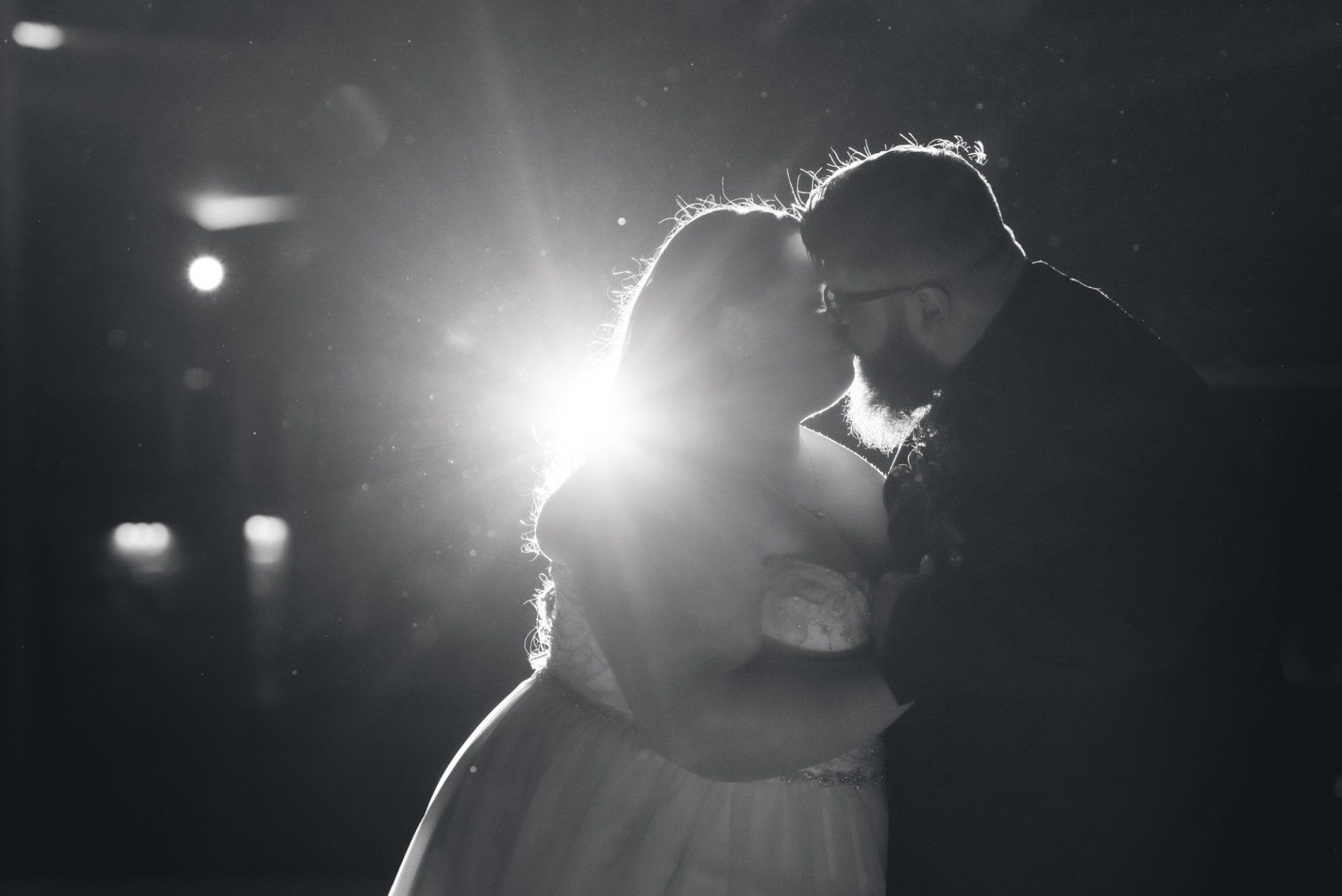 A black and white photo of a bride and groom dancing in the dark.