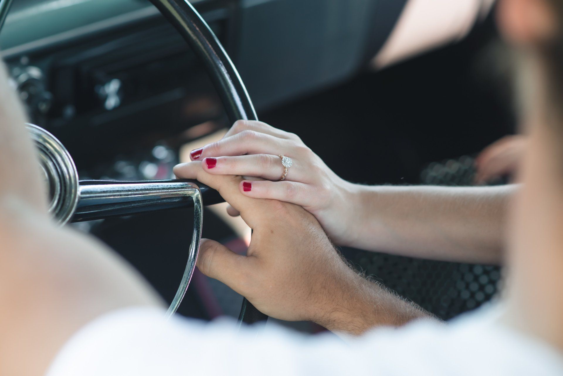 A woman is holding a man 's hand while driving a car.