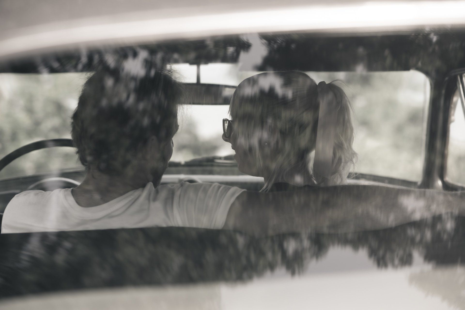 A man and a woman are sitting in the back seat of a car.