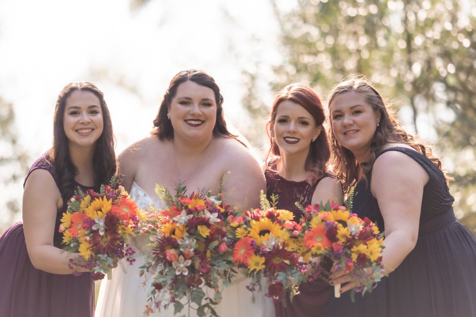 A bride and her bridesmaids are posing for a picture while holding bouquets of flowers.
