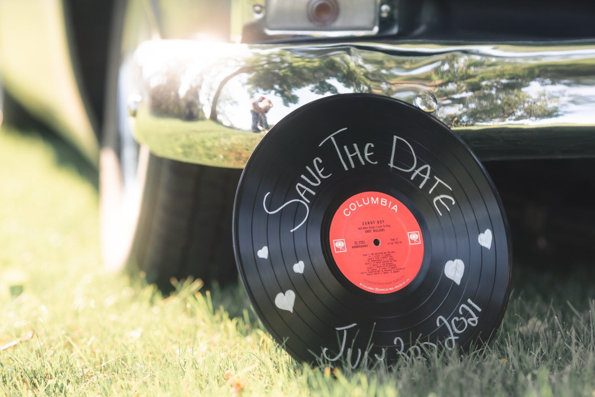 A record is sitting in the grass next to a car.