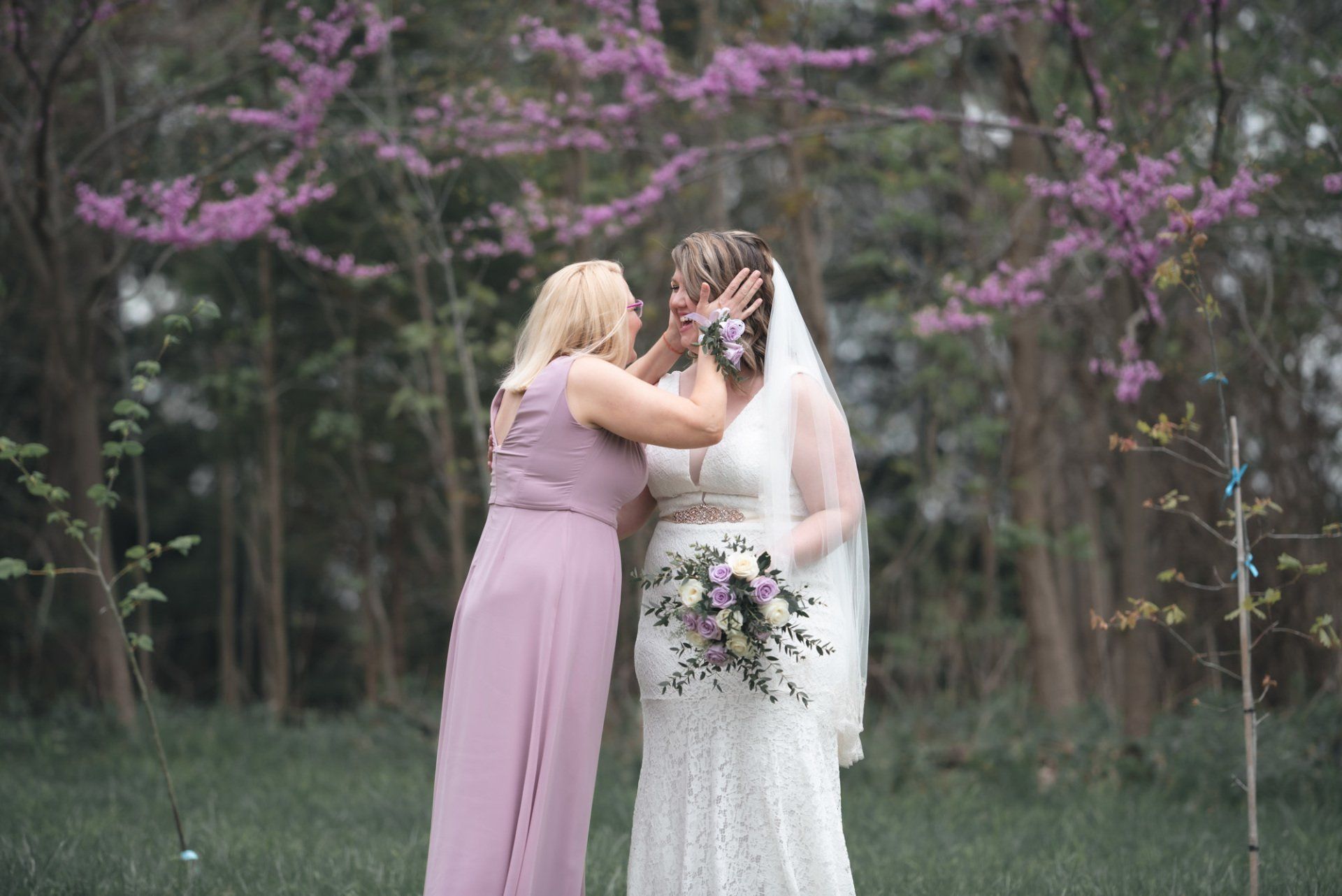 A bride and her bridesmaid are standing next to each other in a field.