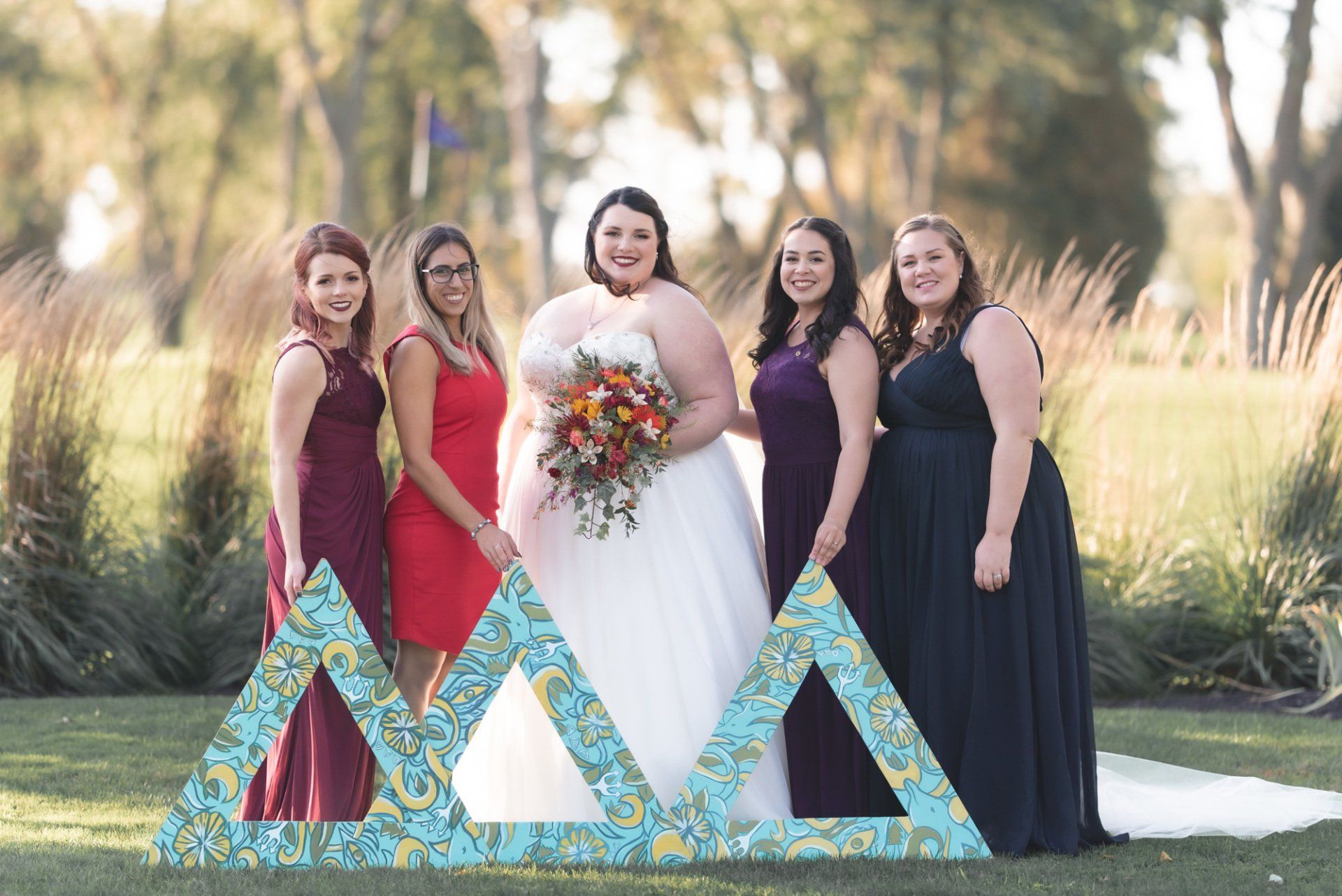 A bride and her bridesmaids are posing for a picture in front of a large triangle.