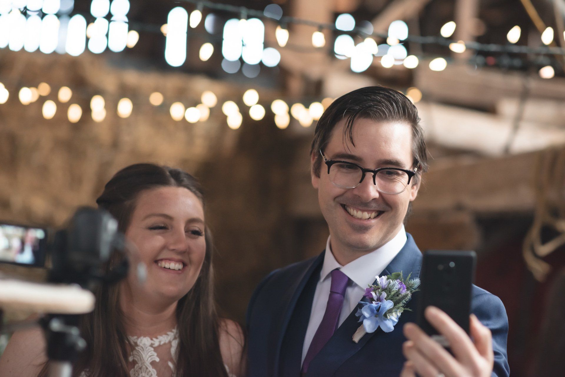 A bride and groom are taking a selfie with a cell phone.