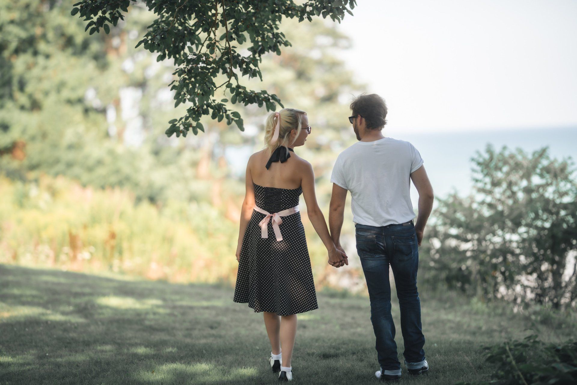 A man and a woman are holding hands while walking in a park.