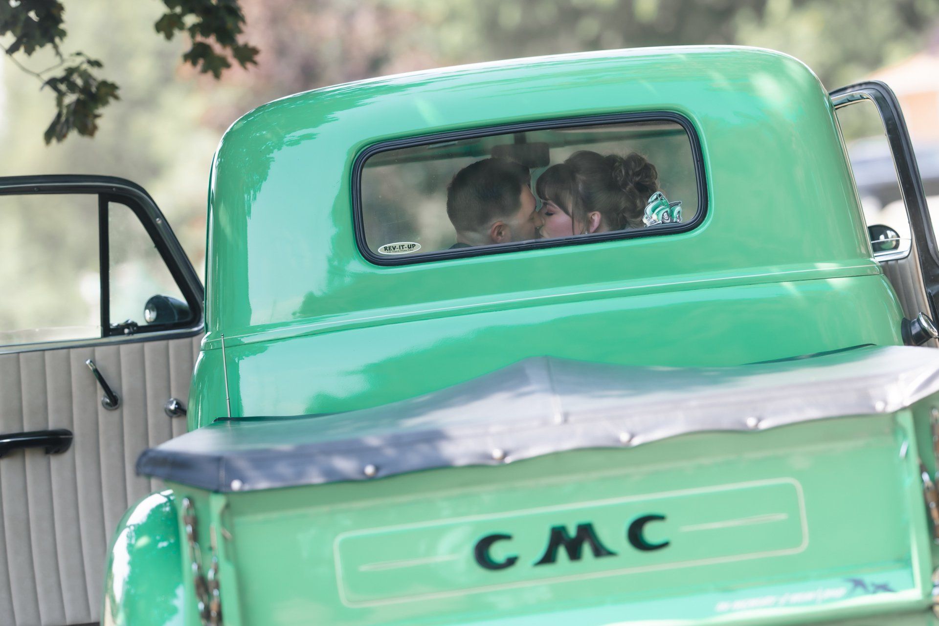 A couple is sitting in the back of a green gmc truck.