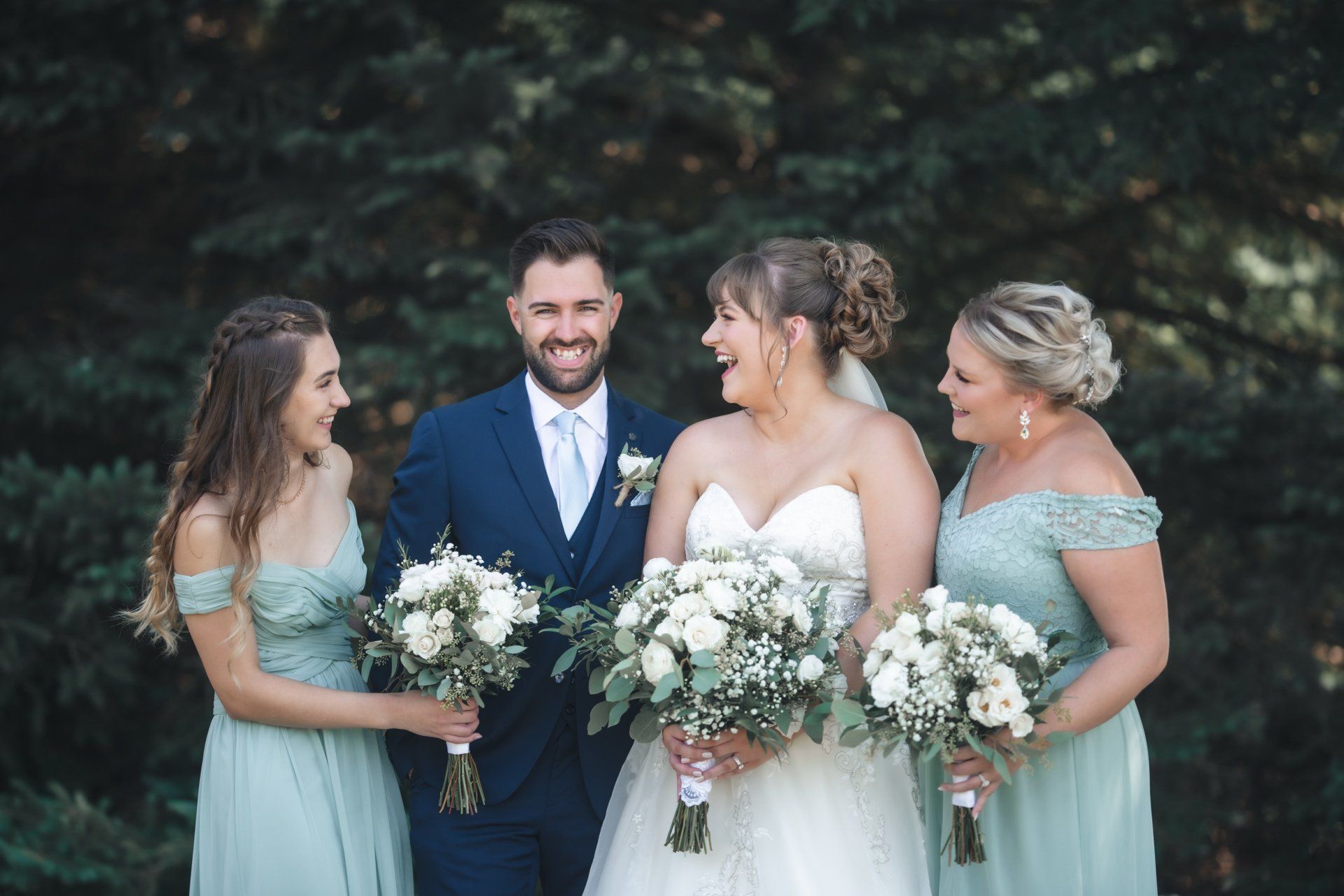 A bride and groom are posing for a picture with their bridesmaids.