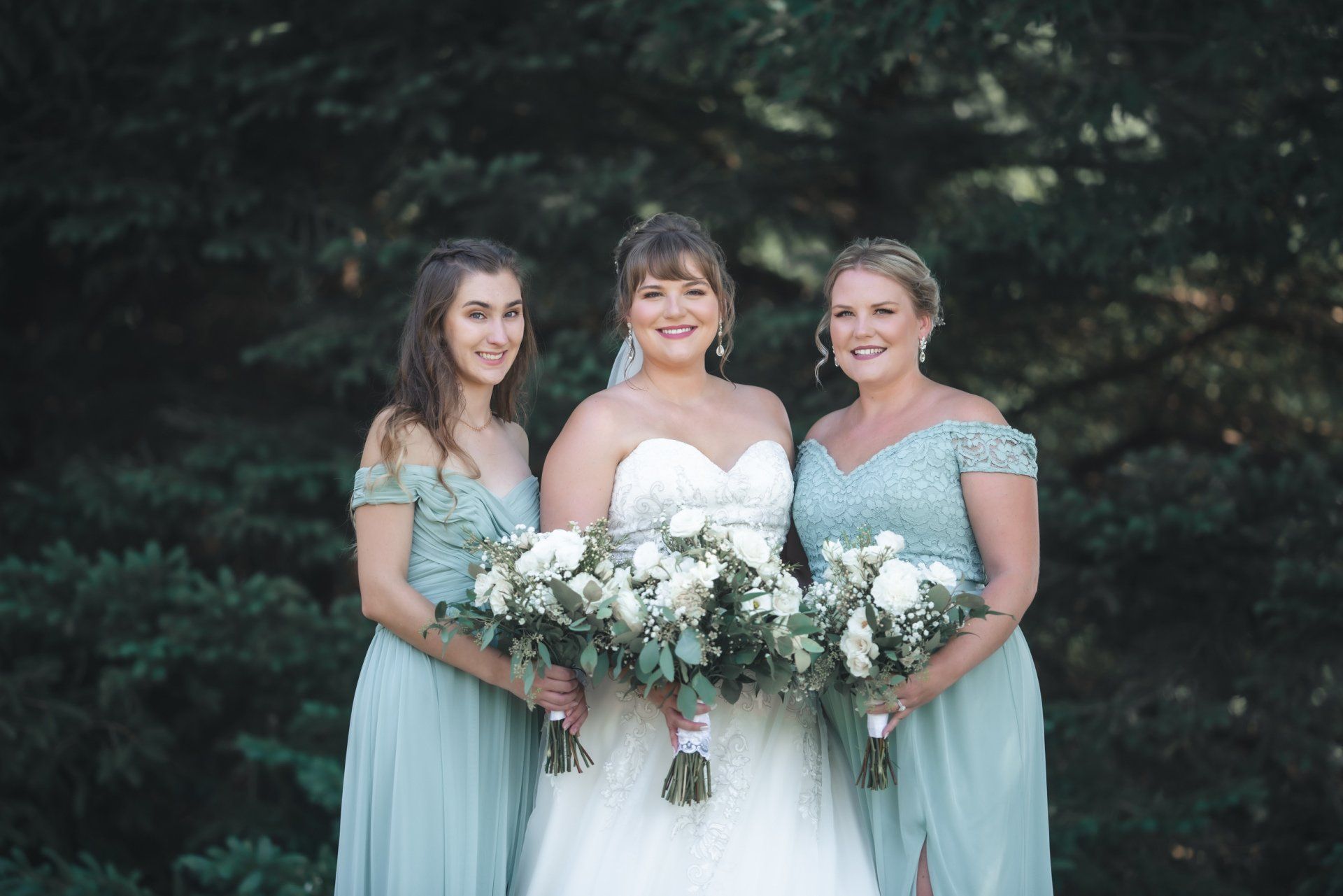 A bride and her two bridesmaids are posing for a picture.