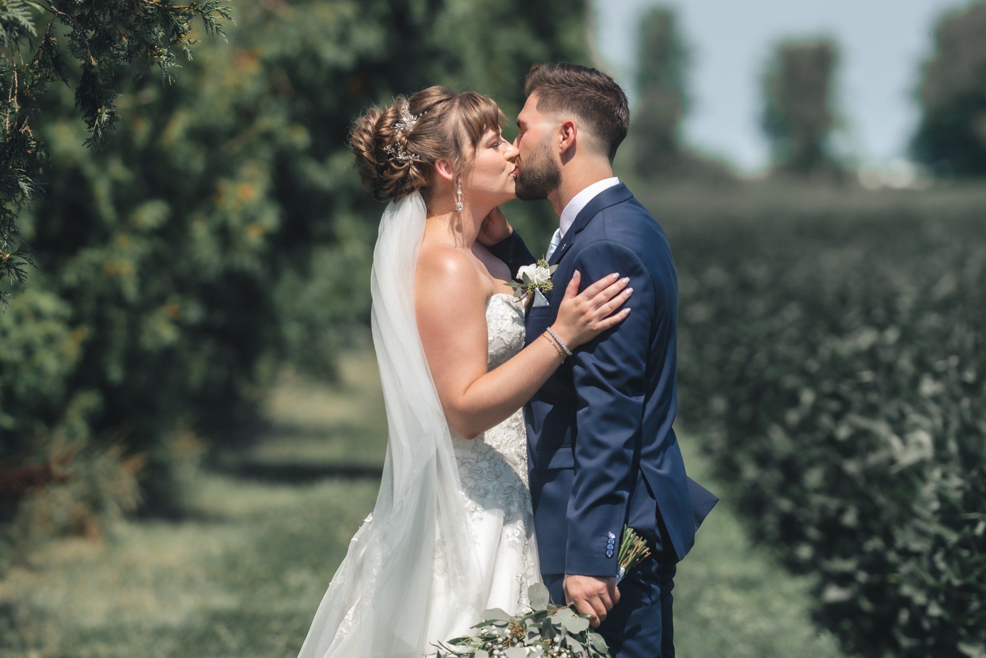 A bride and groom are kissing in a field.