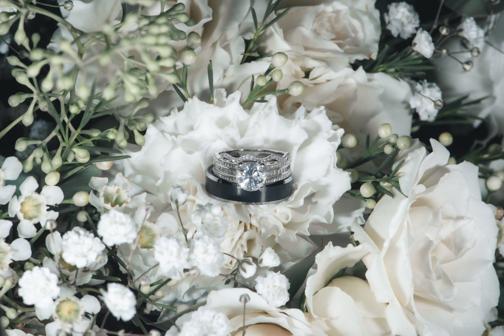 A wedding ring is sitting on top of a bouquet of white flowers.
