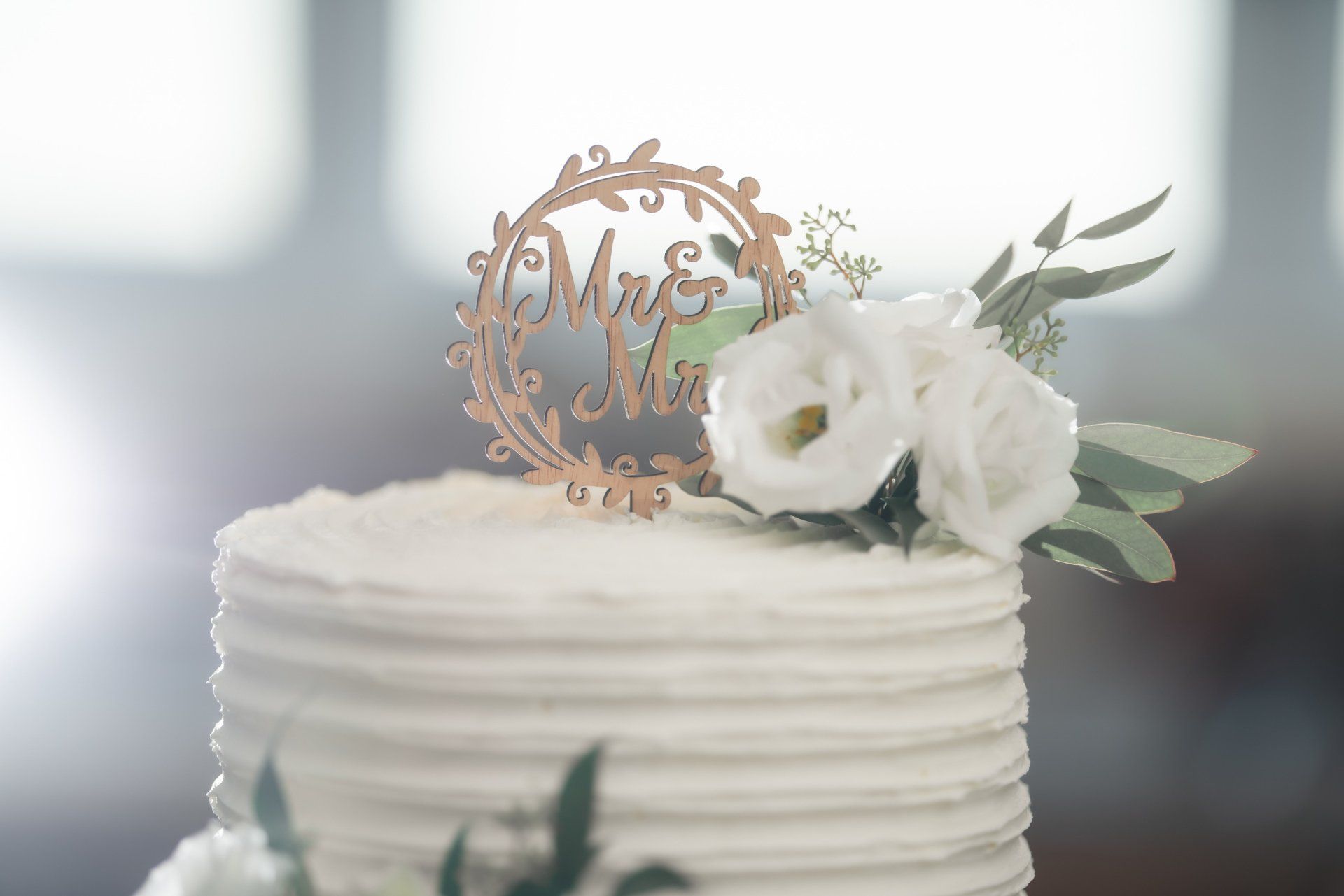 A close up of a wedding cake with flowers and a cake topper.
