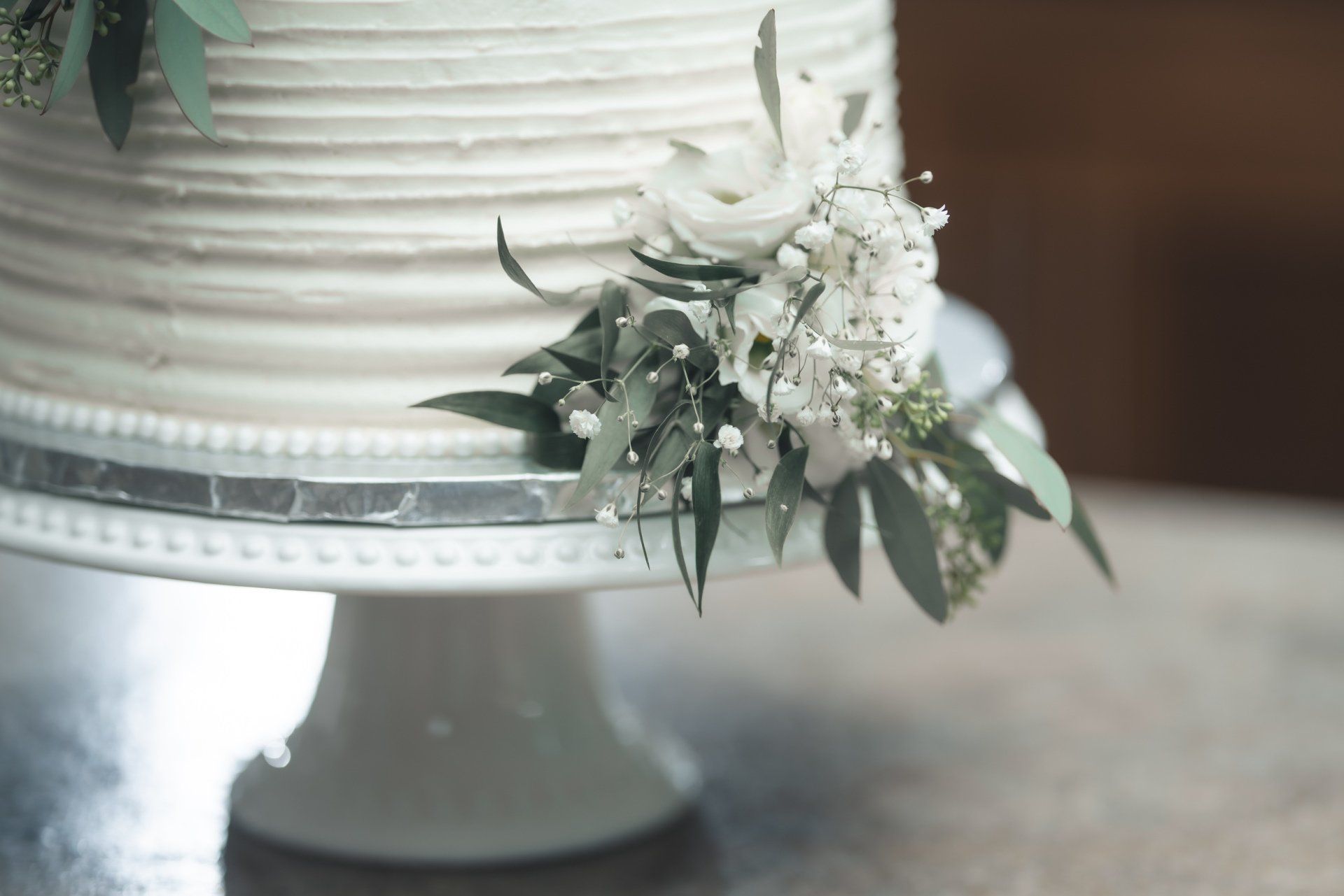 A close up of a wedding cake on a cake stand on a table.