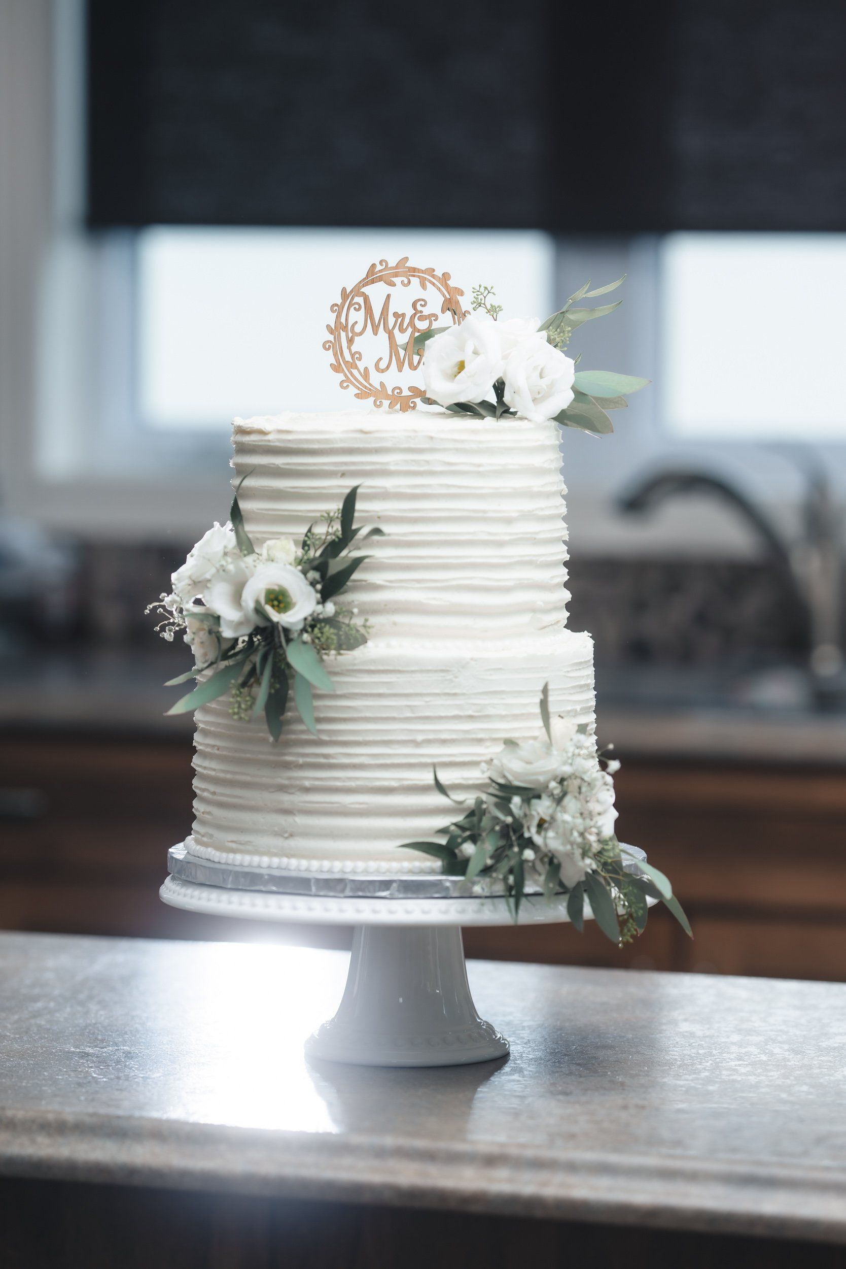 A white wedding cake with flowers on top is sitting on a table.