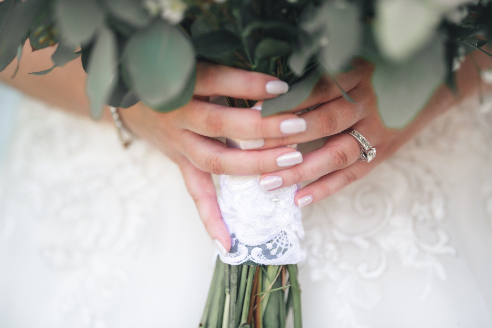 A bride is holding a bouquet of flowers in her hands.