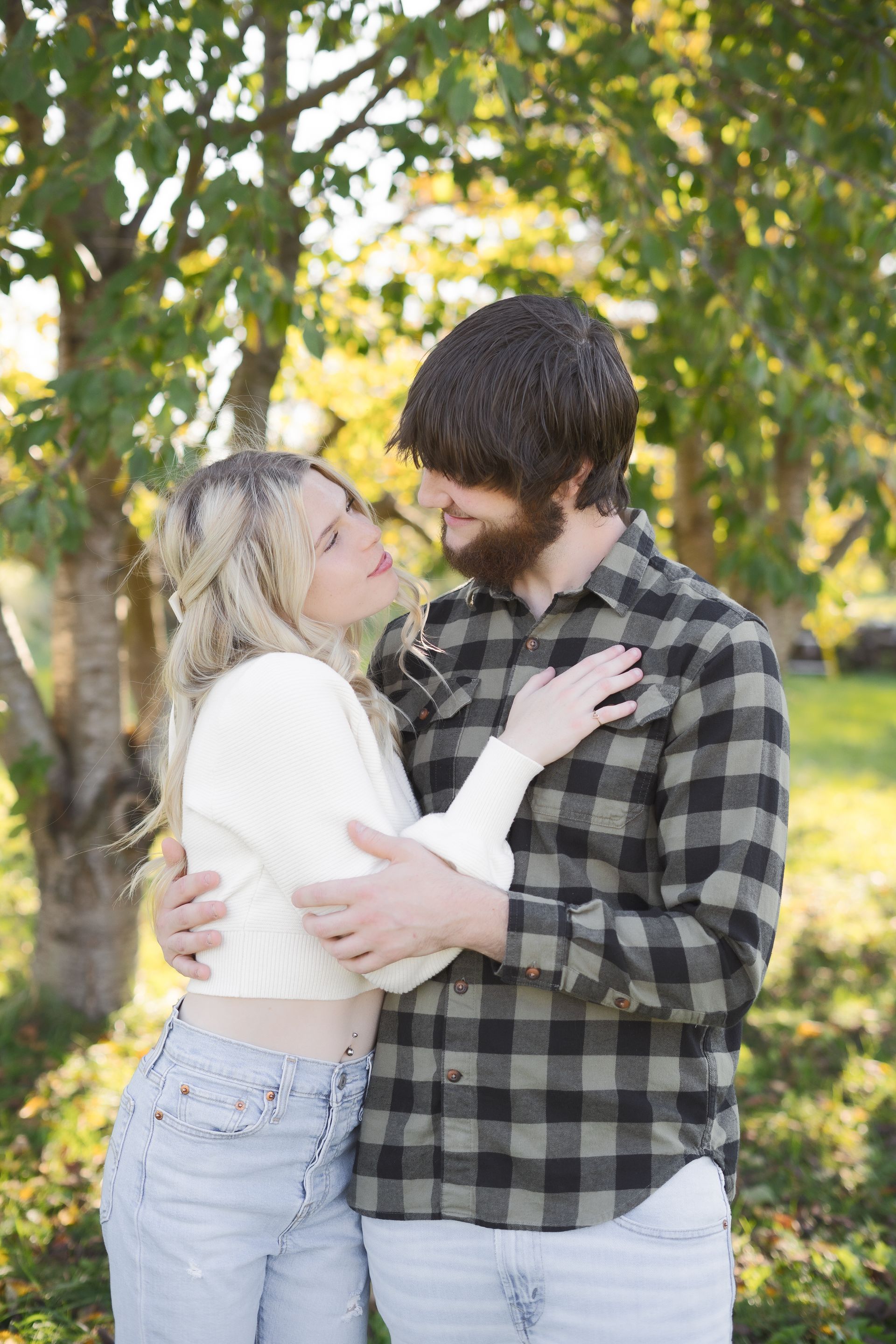 A man and a woman are hugging each other in a park.