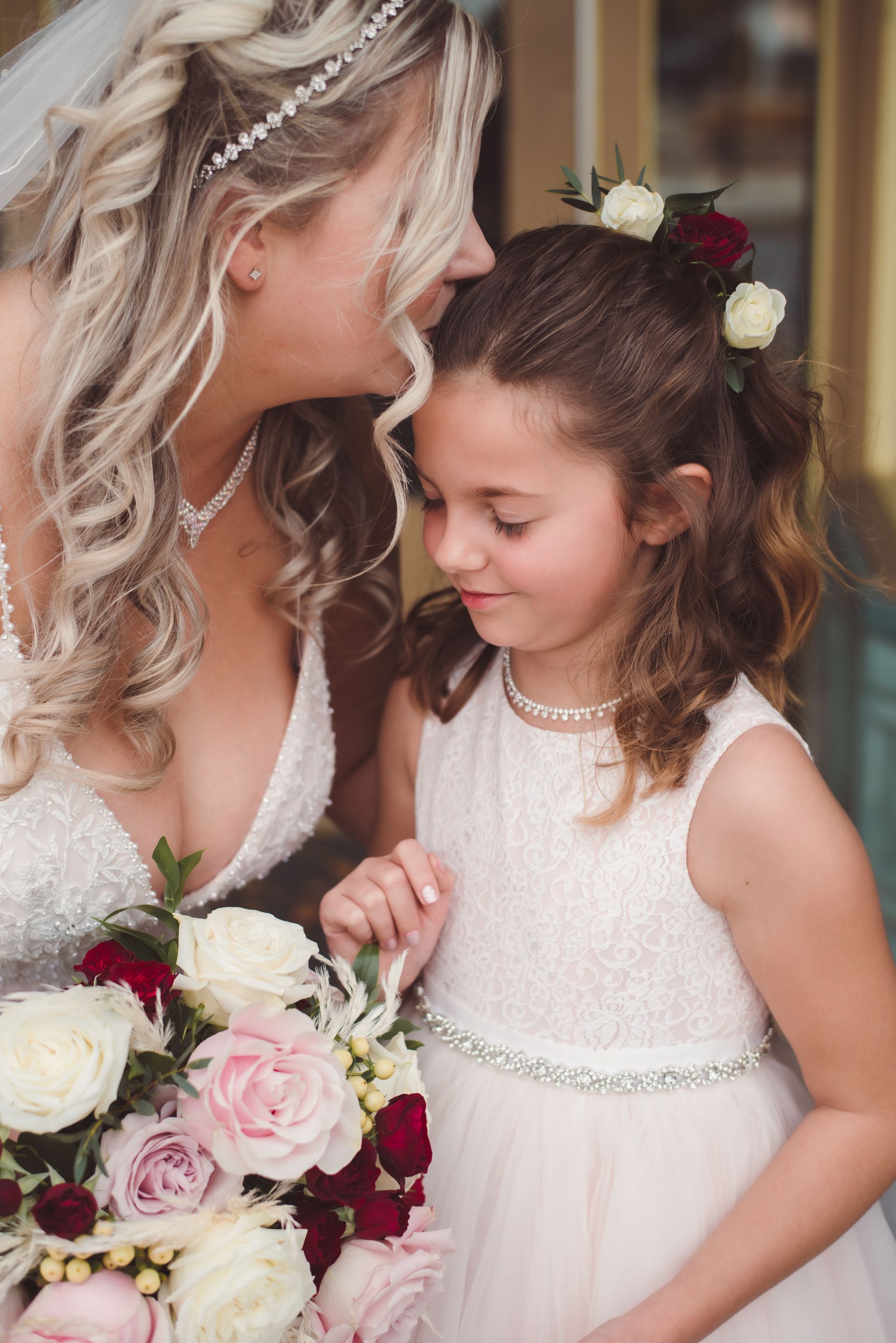 Close up Portrait of bride, kissing, forehead of flower girl, Retro Suites Hotel, vintage wedding