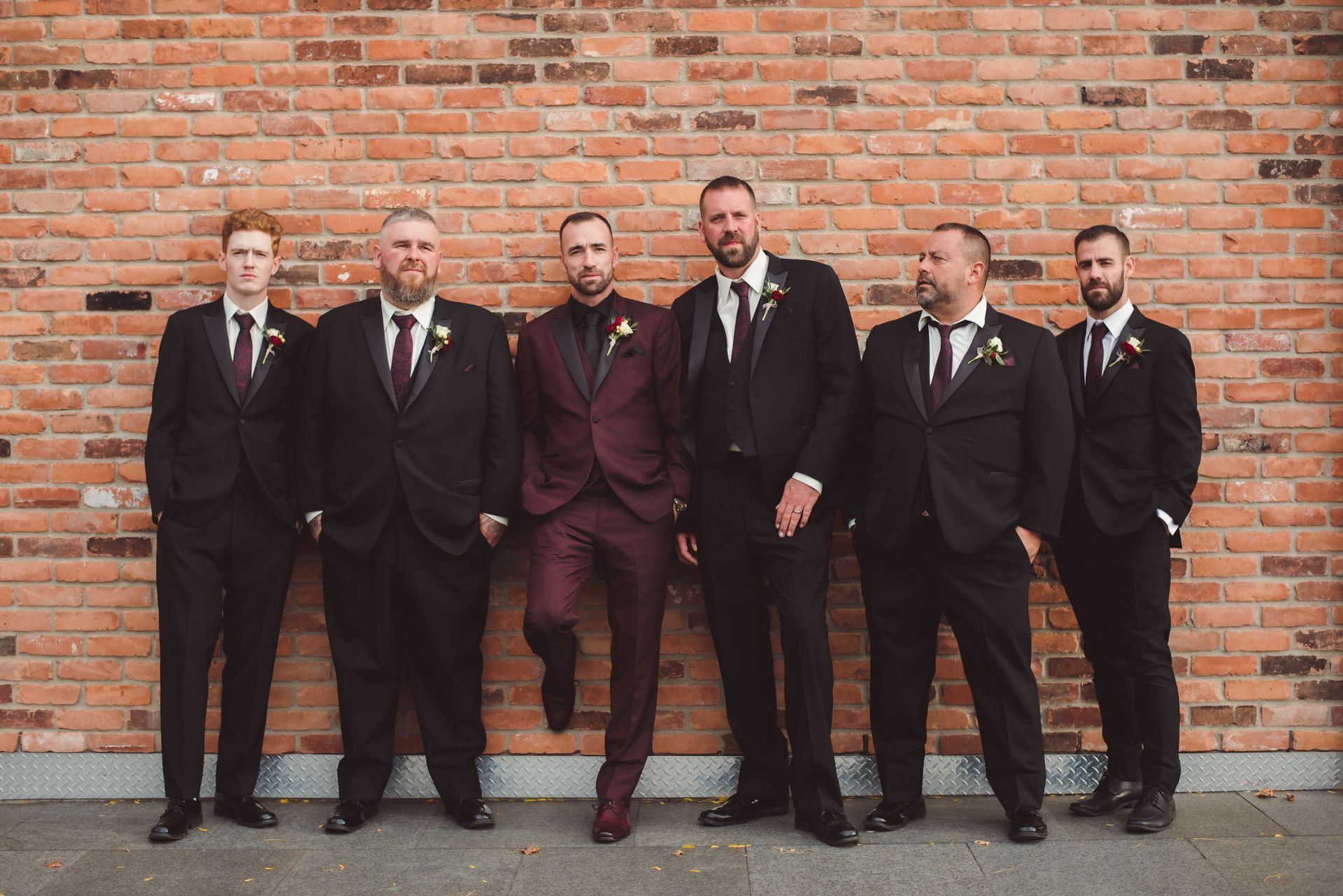 Groom and groomsmen along a brick wall, Retro Suites Hotel, vintage wedding