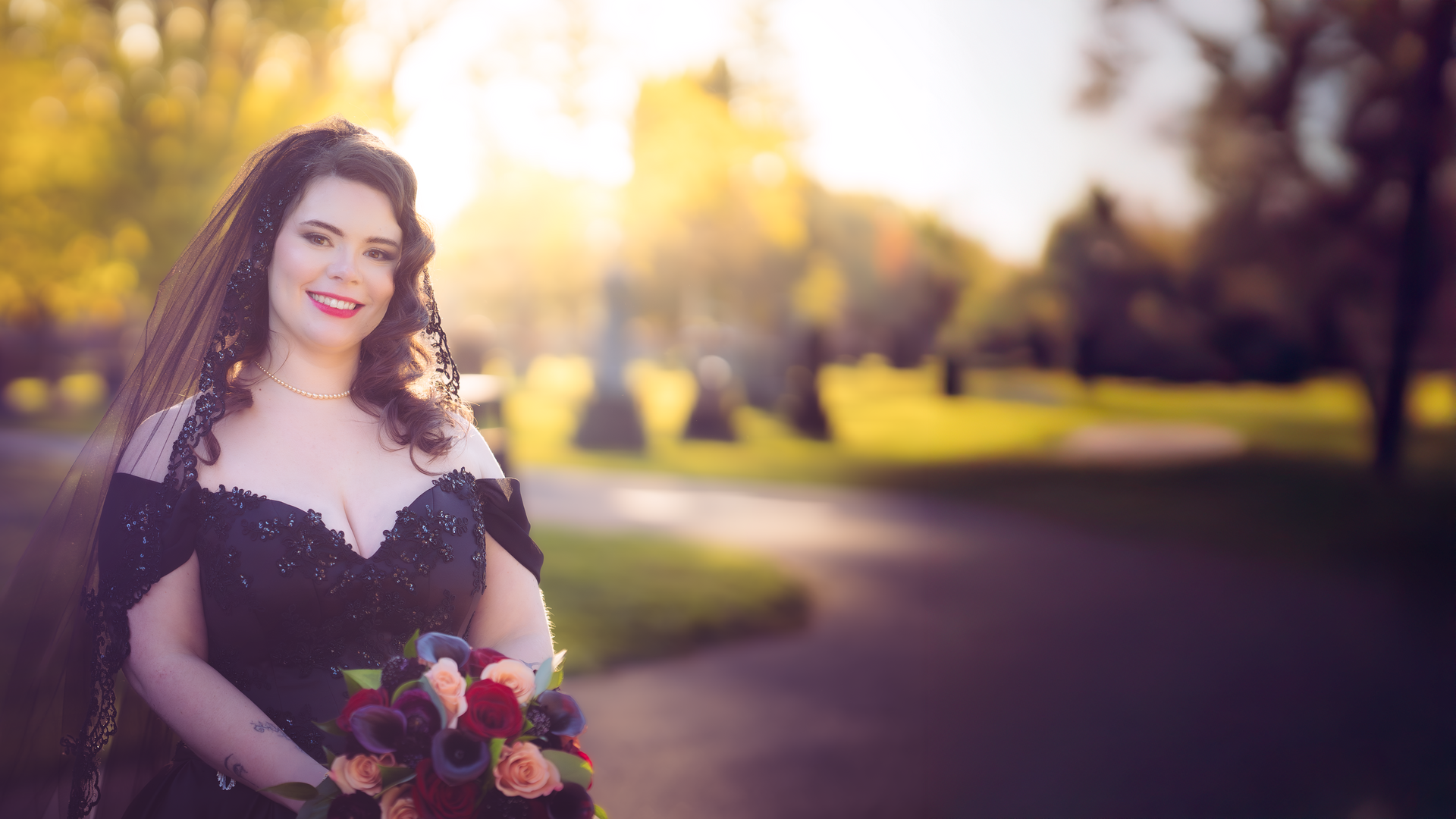 A woman in a black dress and veil is holding a bouquet of flowers.