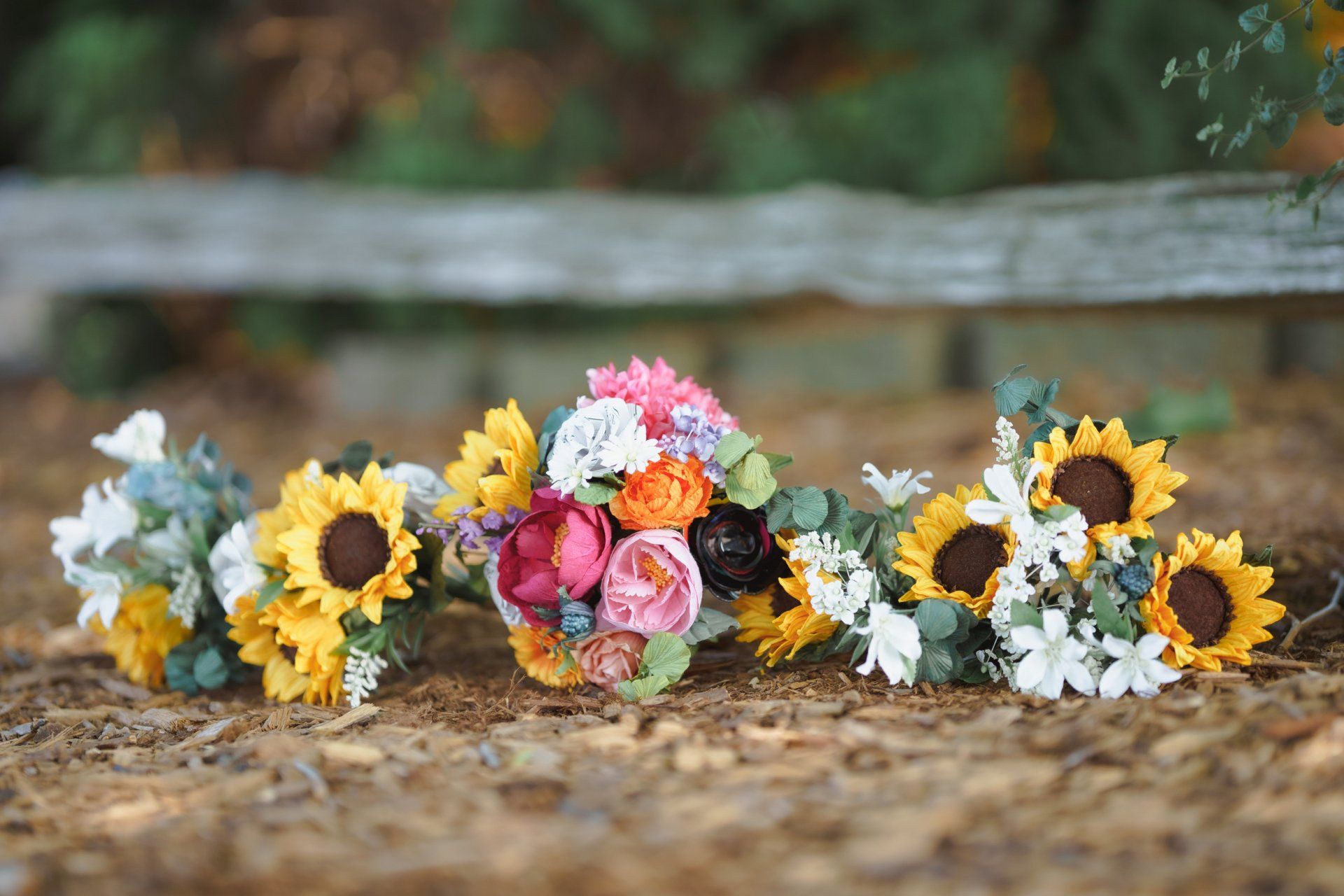 A bunch of flowers are sitting on the ground in front of a wooden fence.