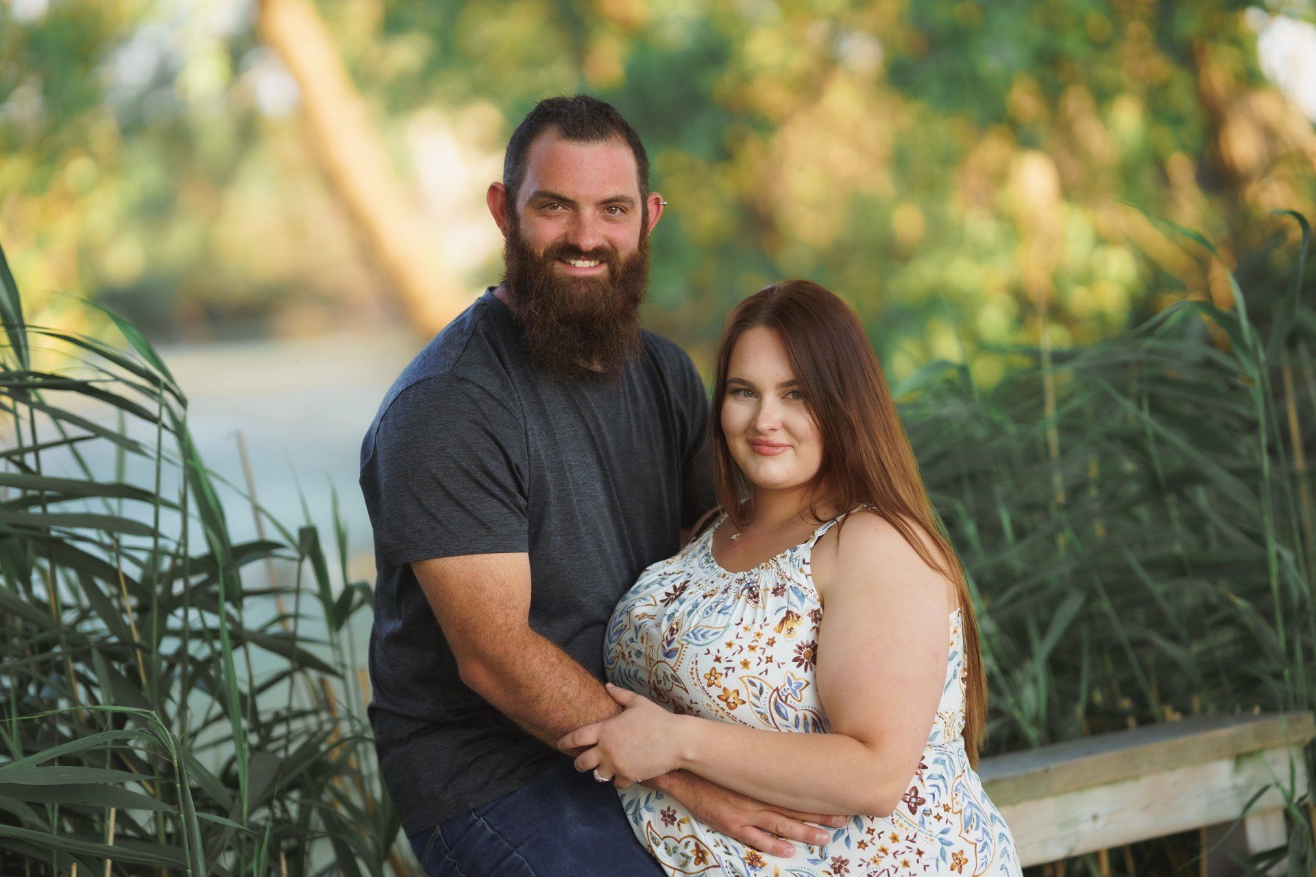A man and a woman are posing for a picture while sitting on a bench.