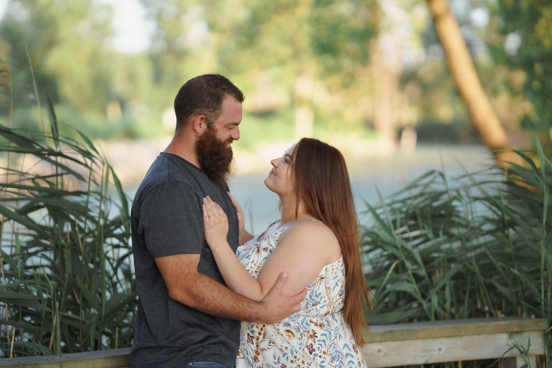 A man and a woman are hugging each other in front of a lake.