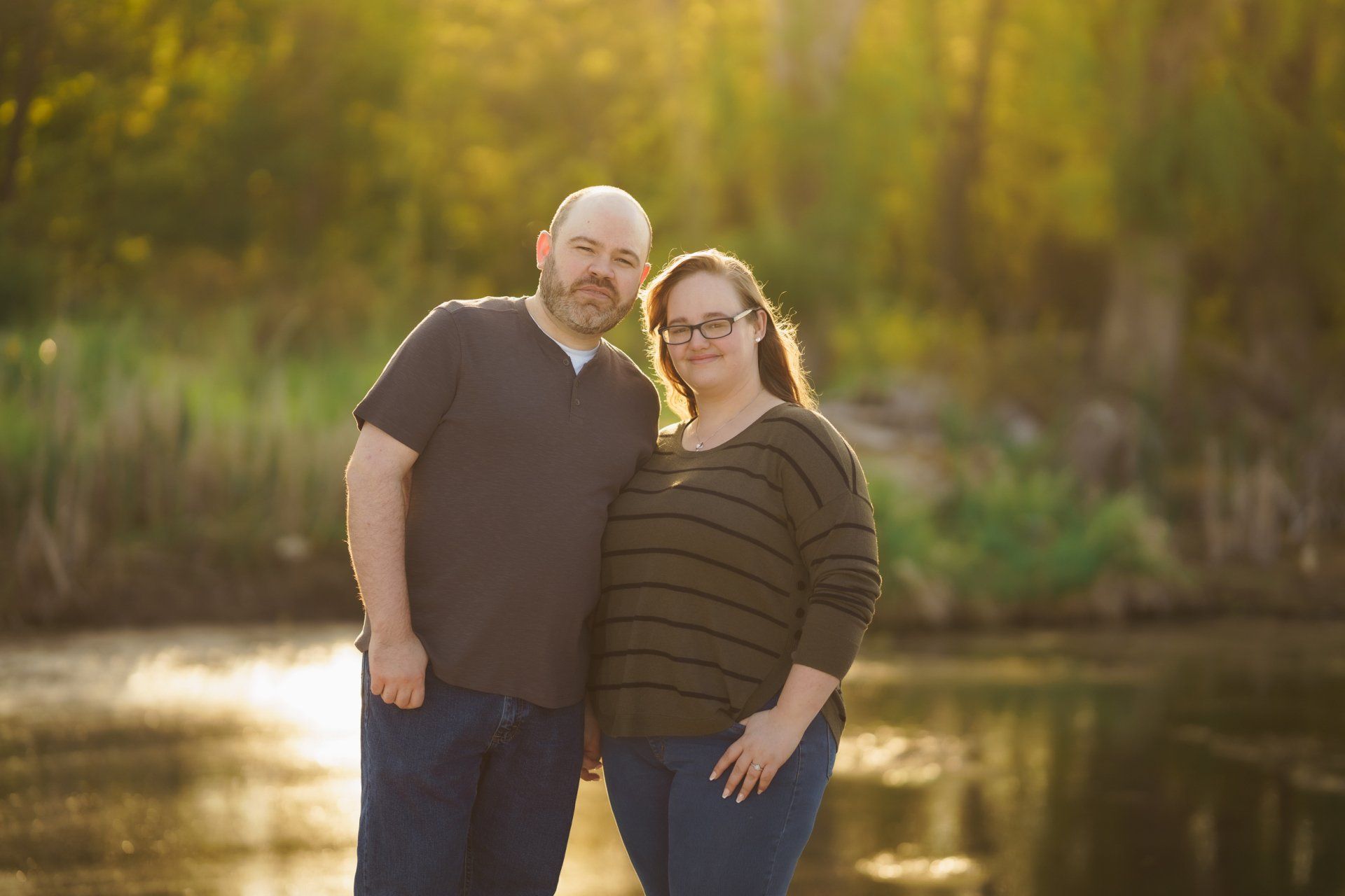 A man and a woman are standing next to each other in front of a body of water.