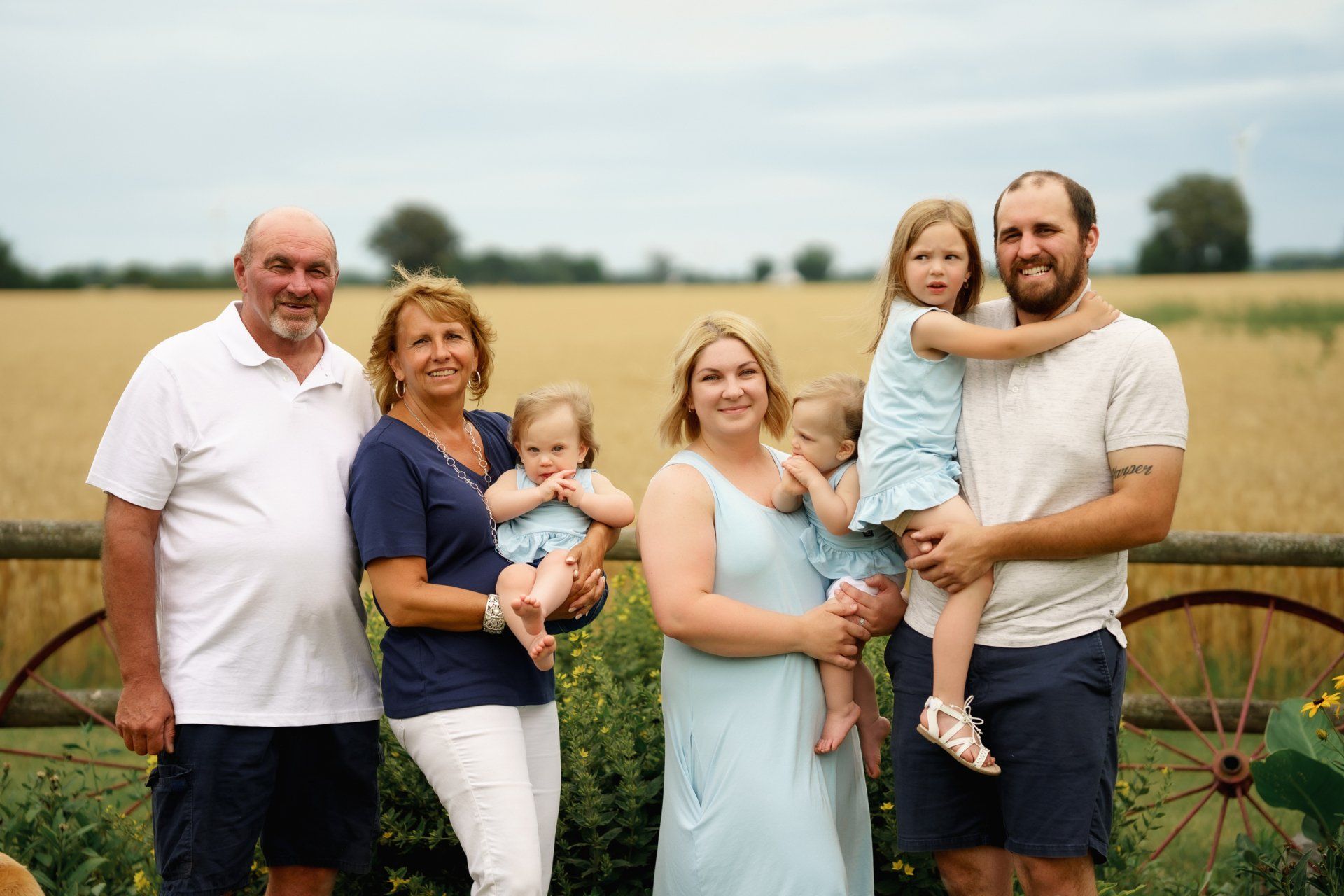A family is posing for a picture in front of a field.