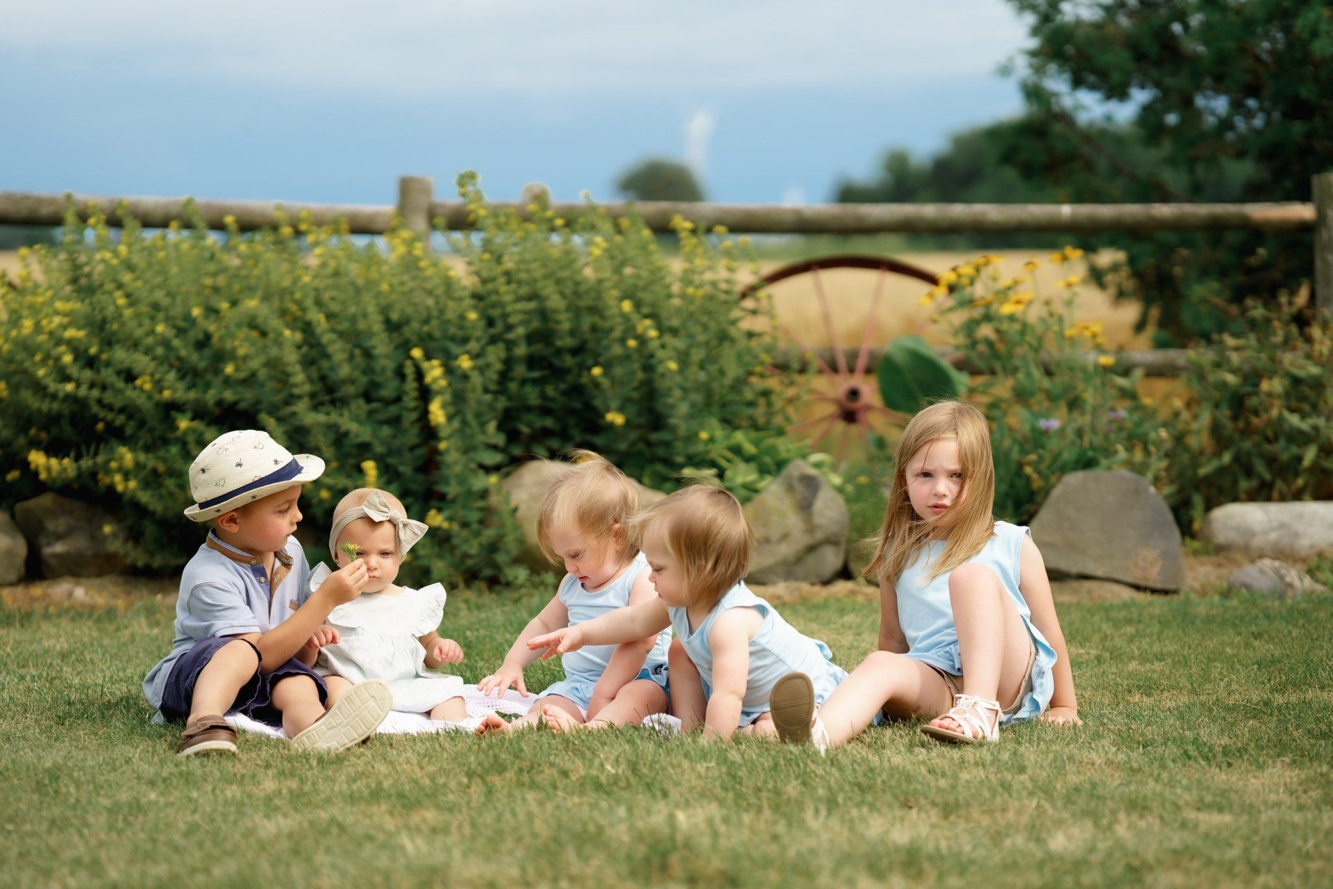 A group of children are sitting on the grass in a field.