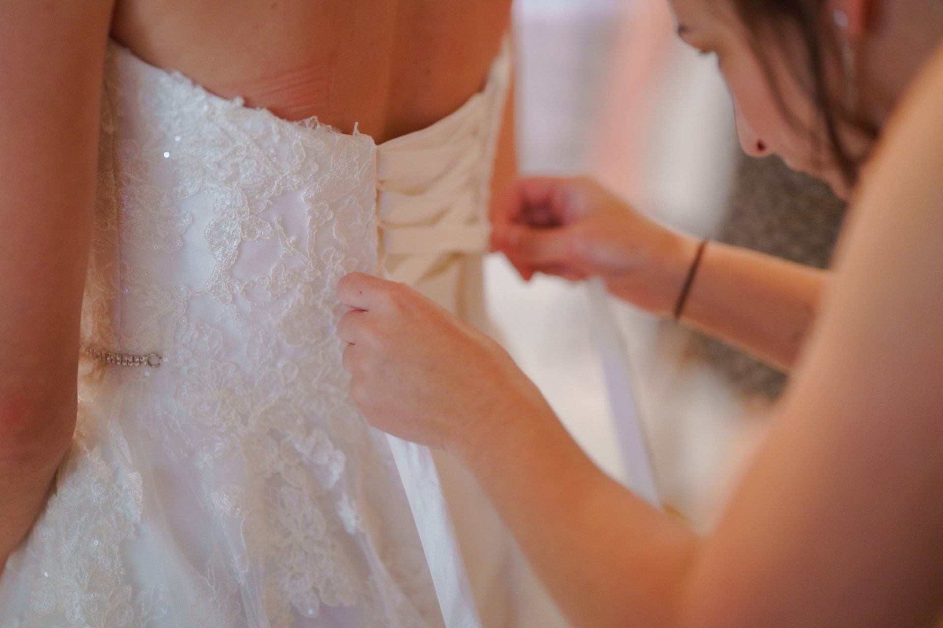 A woman is helping a bride with her wedding dress.