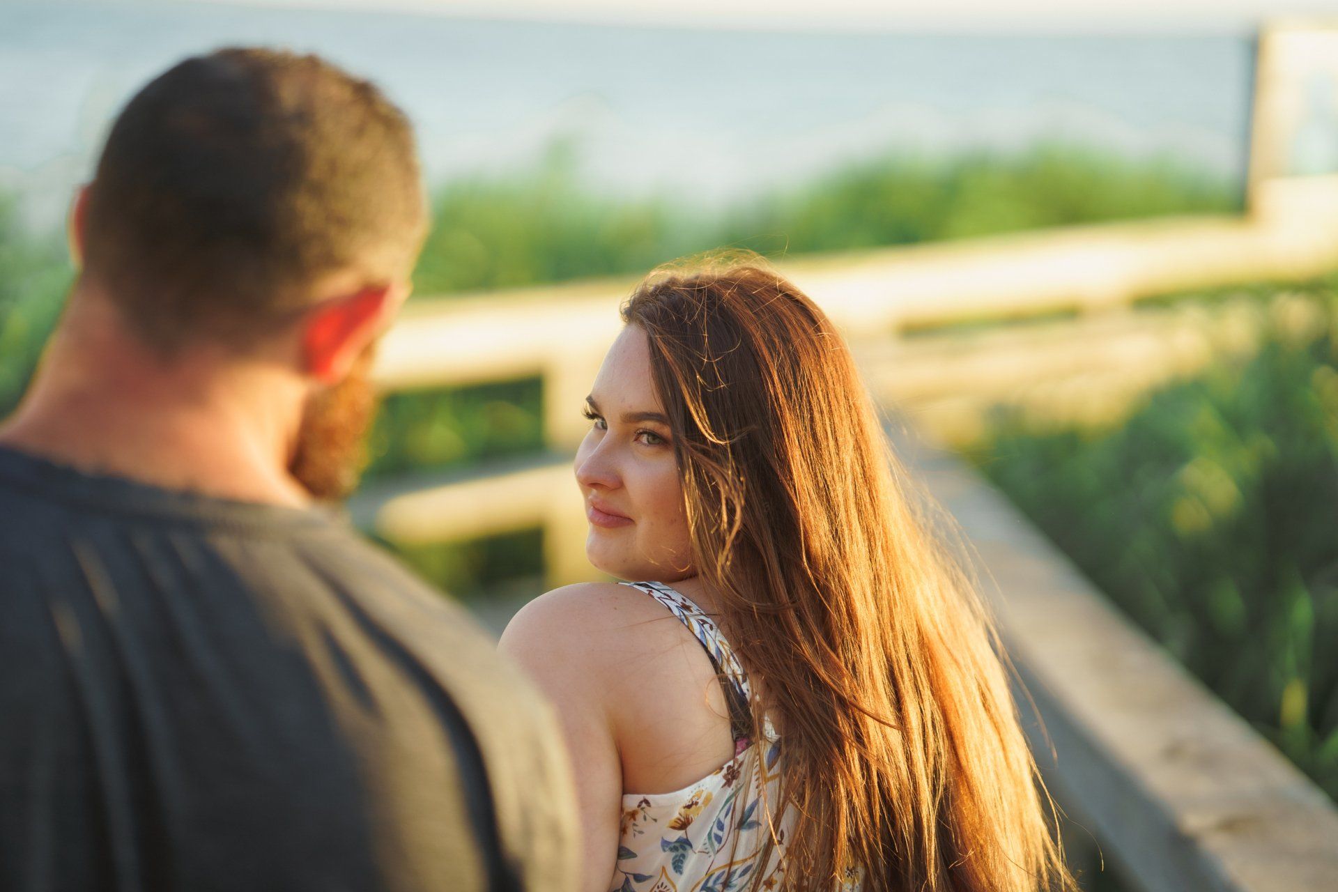 A man and a woman are standing on a bridge looking at each other.