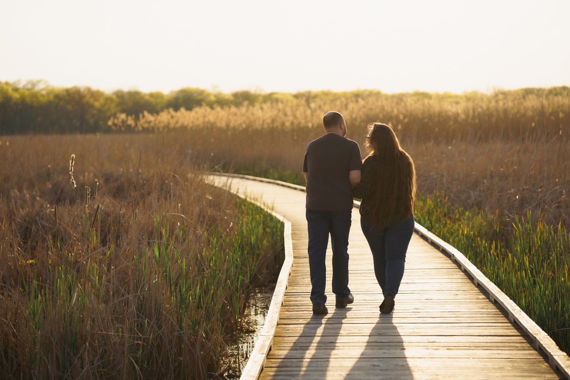 A man and a woman are walking down a wooden walkway.