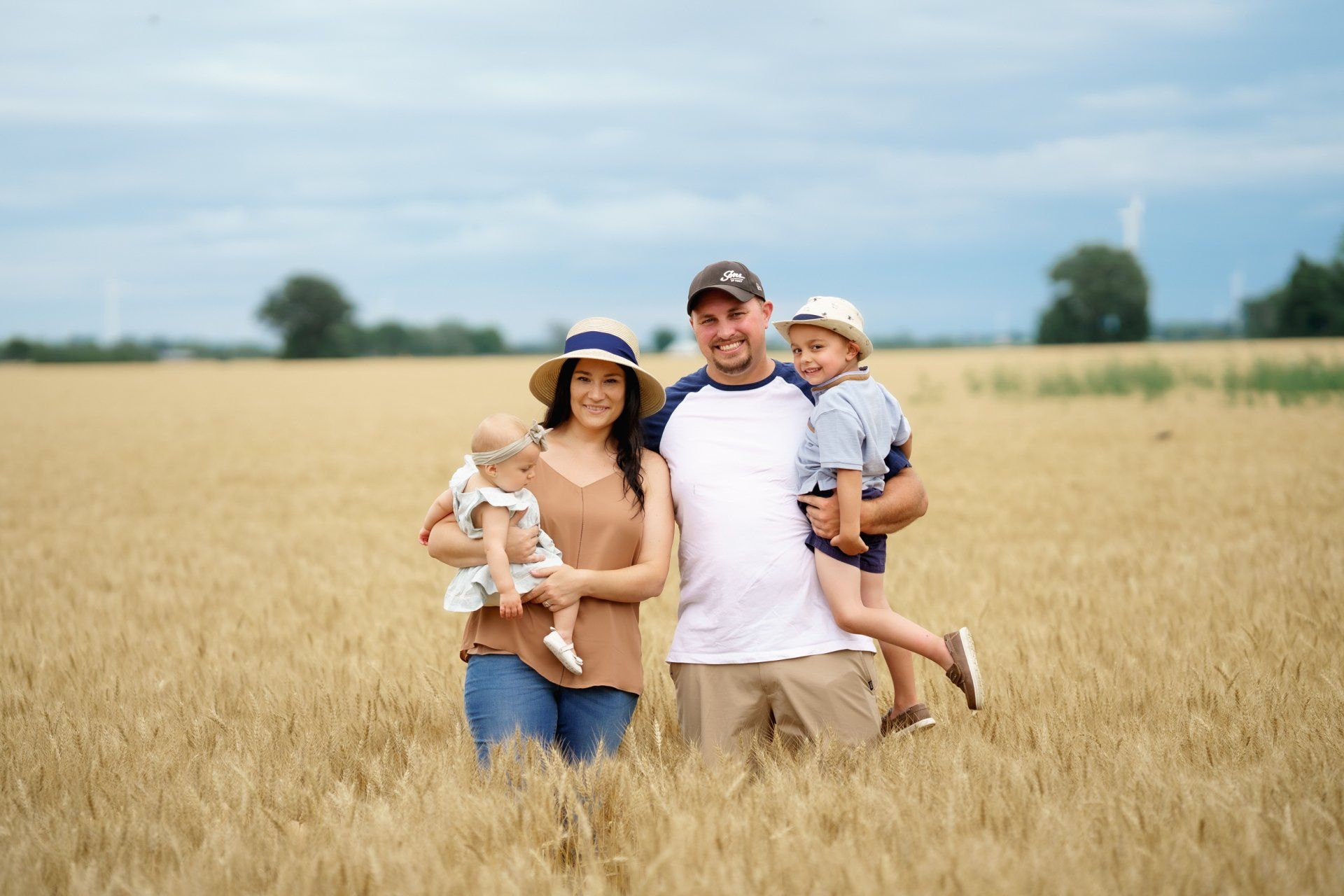 A family is posing for a picture in a wheat field.