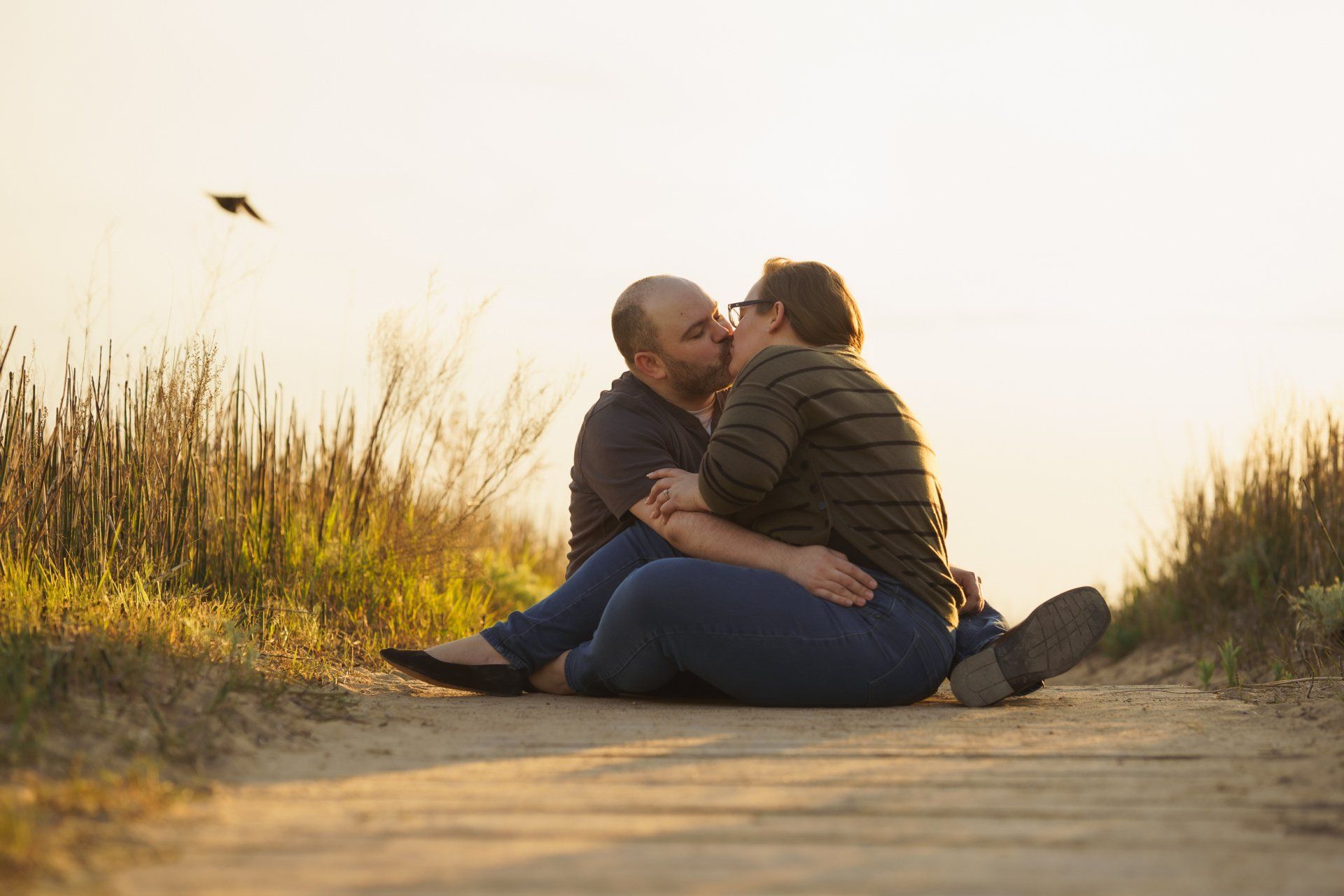 A man and a woman are sitting on the ground kissing.