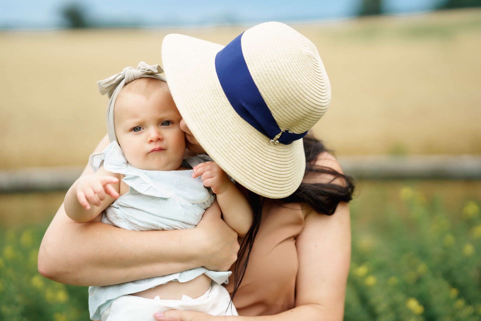 A woman wearing a hat is holding a baby in her arms.
