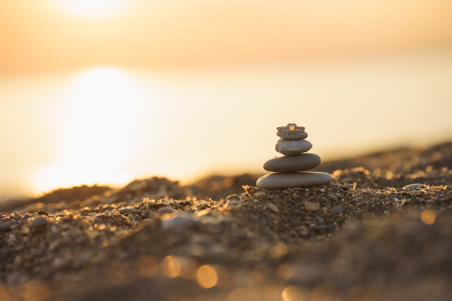 A pile of rocks stacked on top of each other on a beach at sunset.