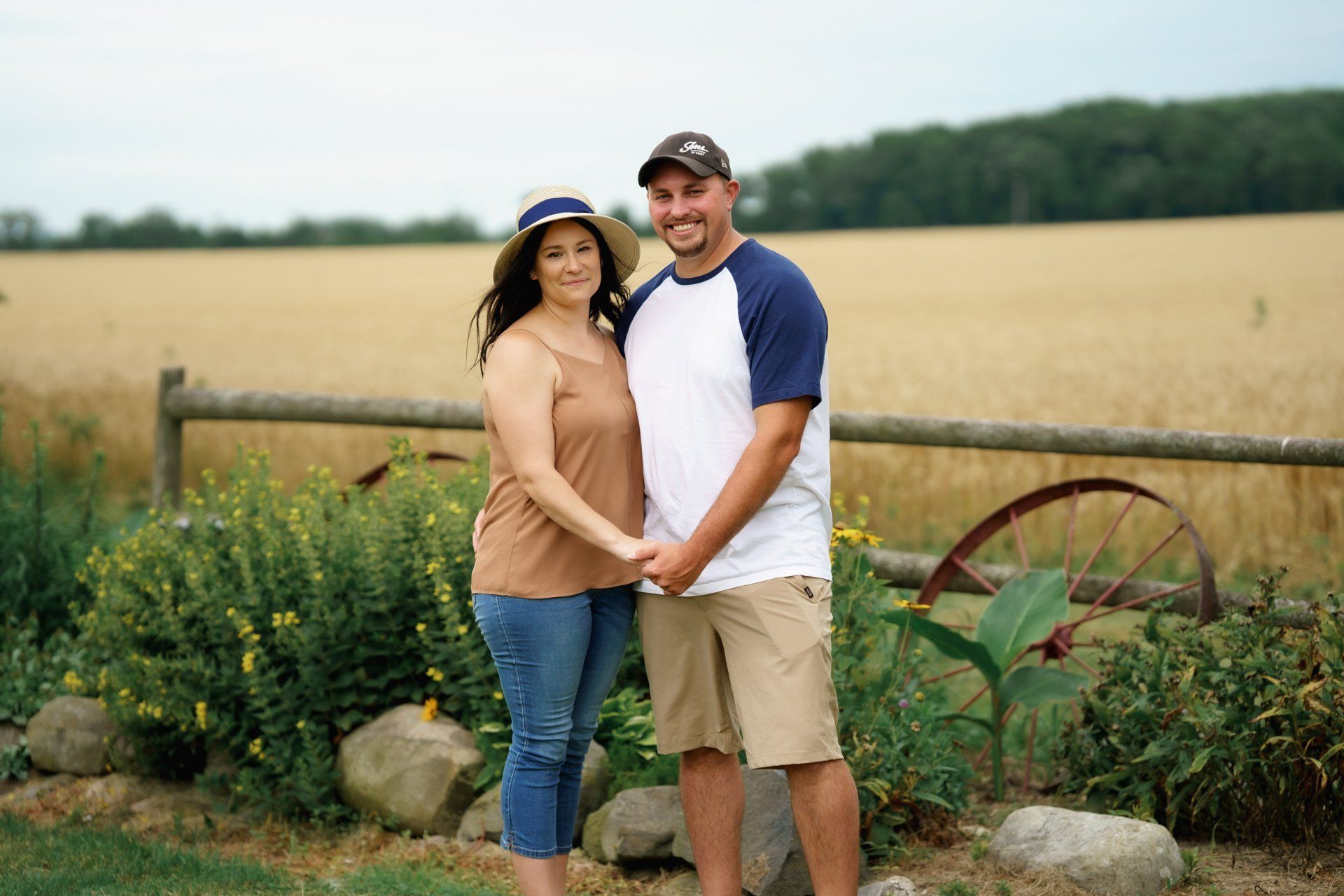 A man and a woman are standing next to each other in front of a field.