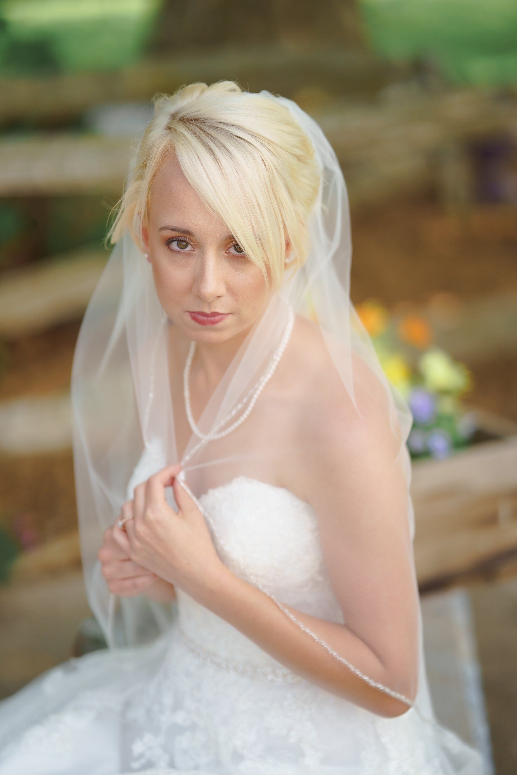 The bride is wearing a veil and a pearl necklace.