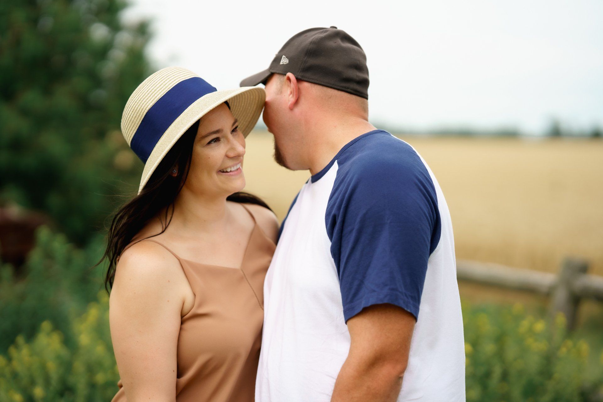 A man and a woman are looking at each other in a field . the woman is wearing a hat.