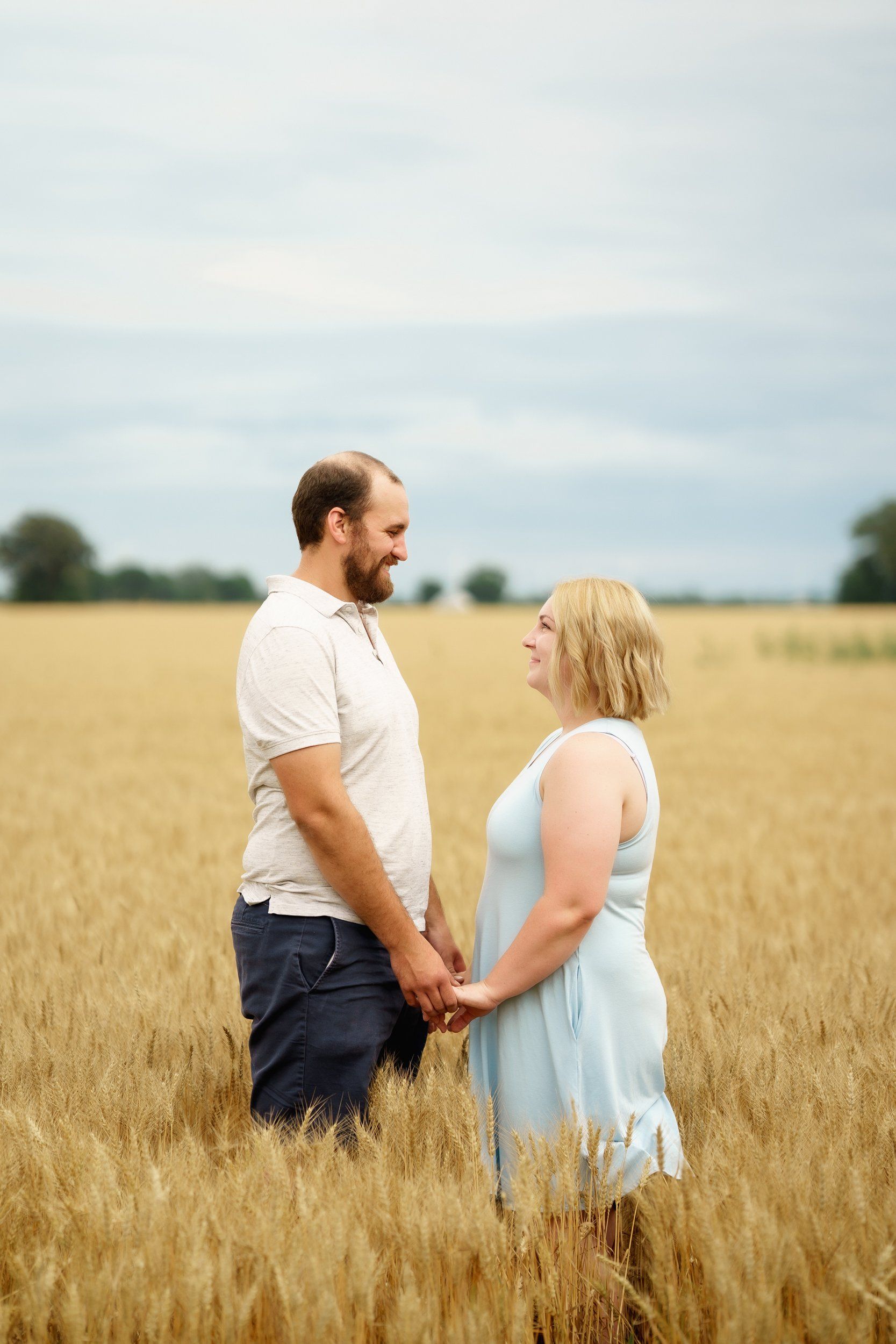 A man and a woman are holding hands in a wheat field.