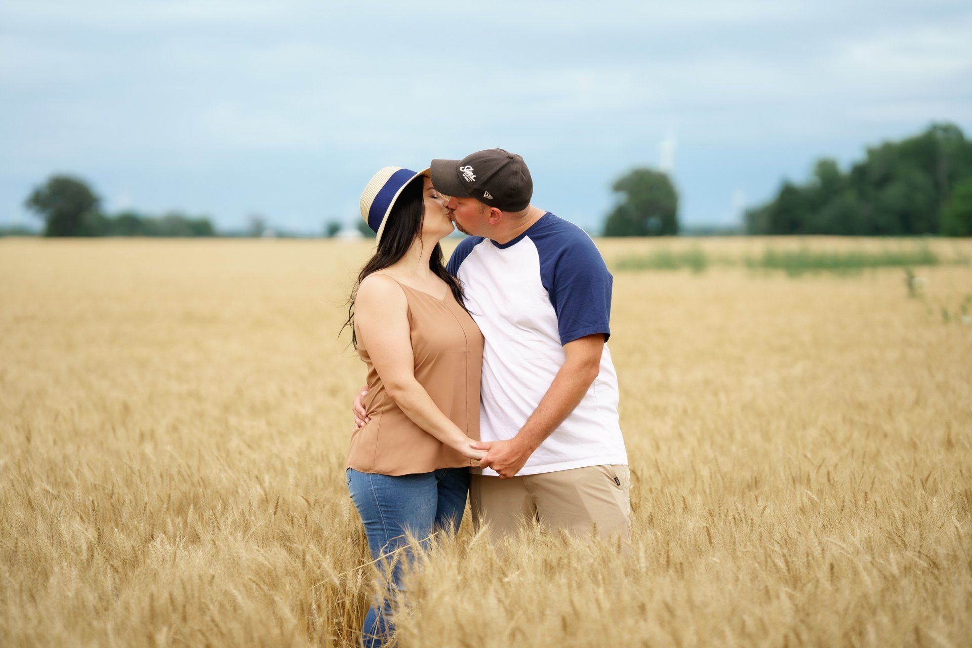 A man and a woman are kissing in a wheat field.