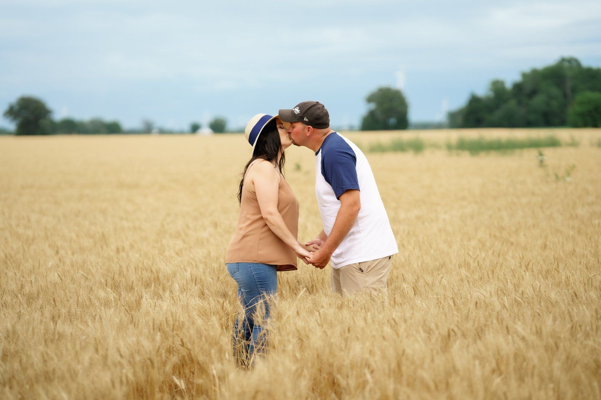 A man and a woman are kissing in a wheat field.