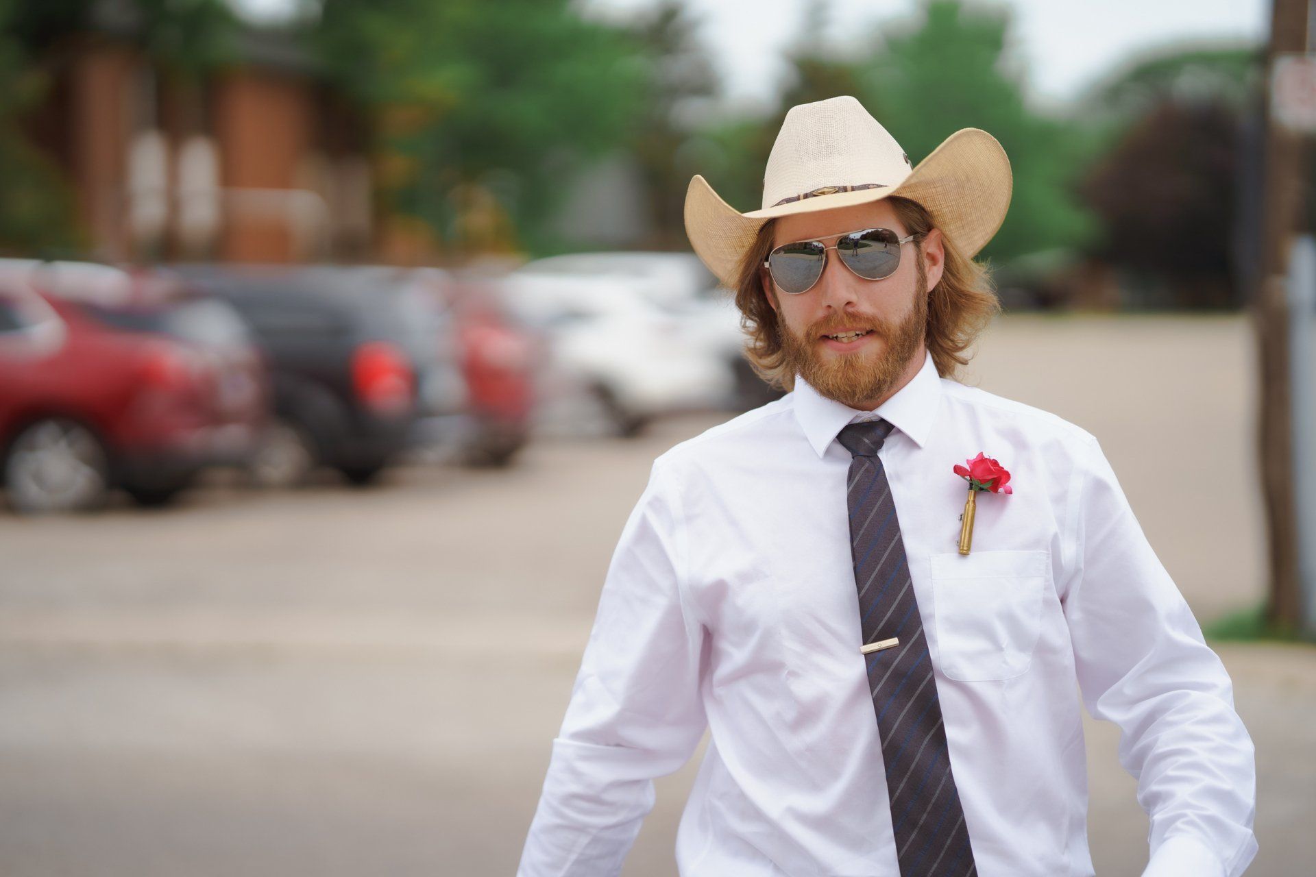 A man wearing a cowboy hat and sunglasses is walking down the street.