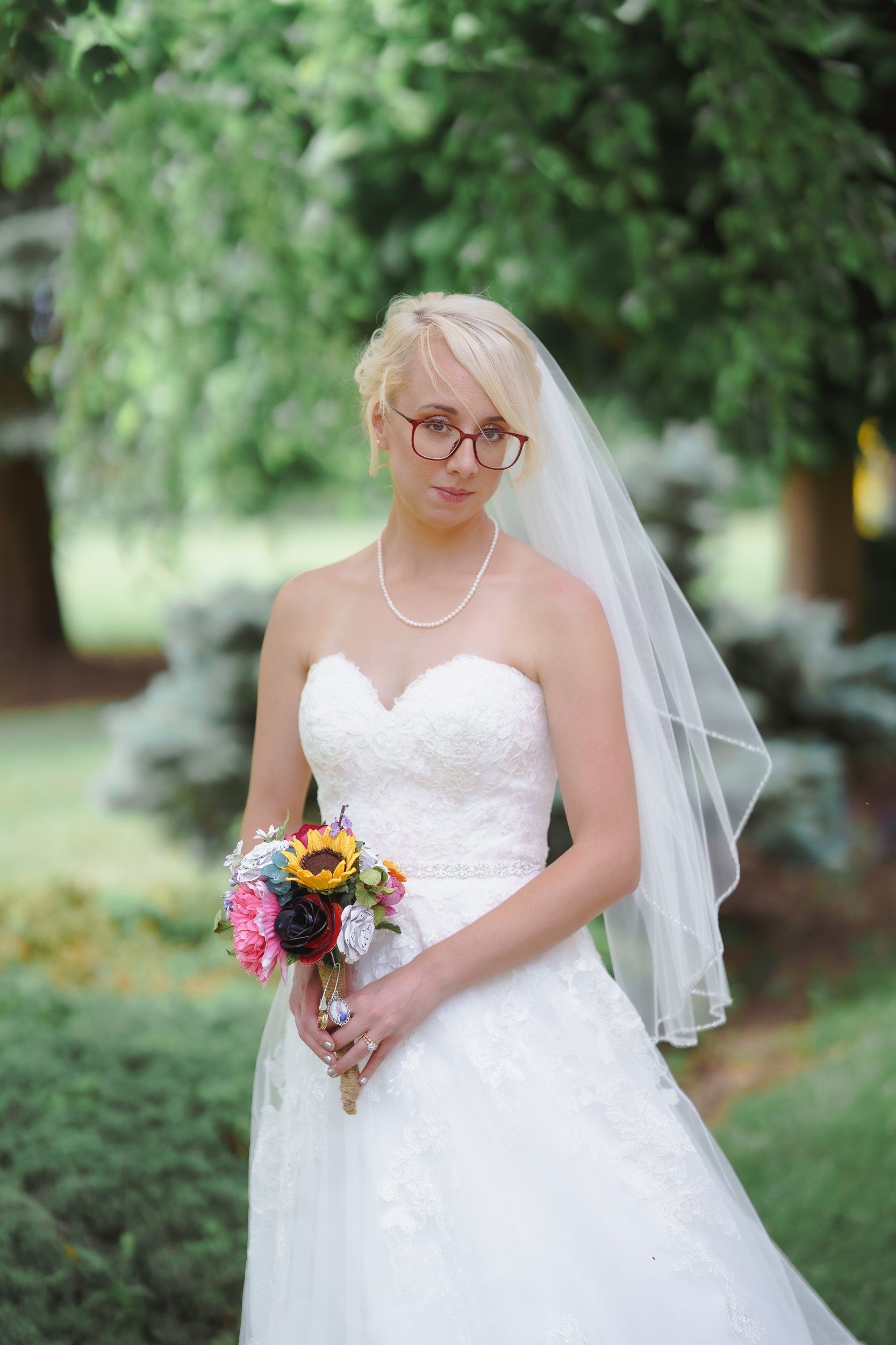 The bride is wearing glasses and holding a bouquet of flowers.