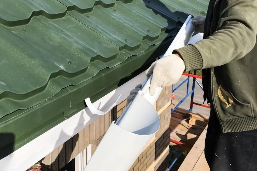 a man is fixing a gutter on a green roof .