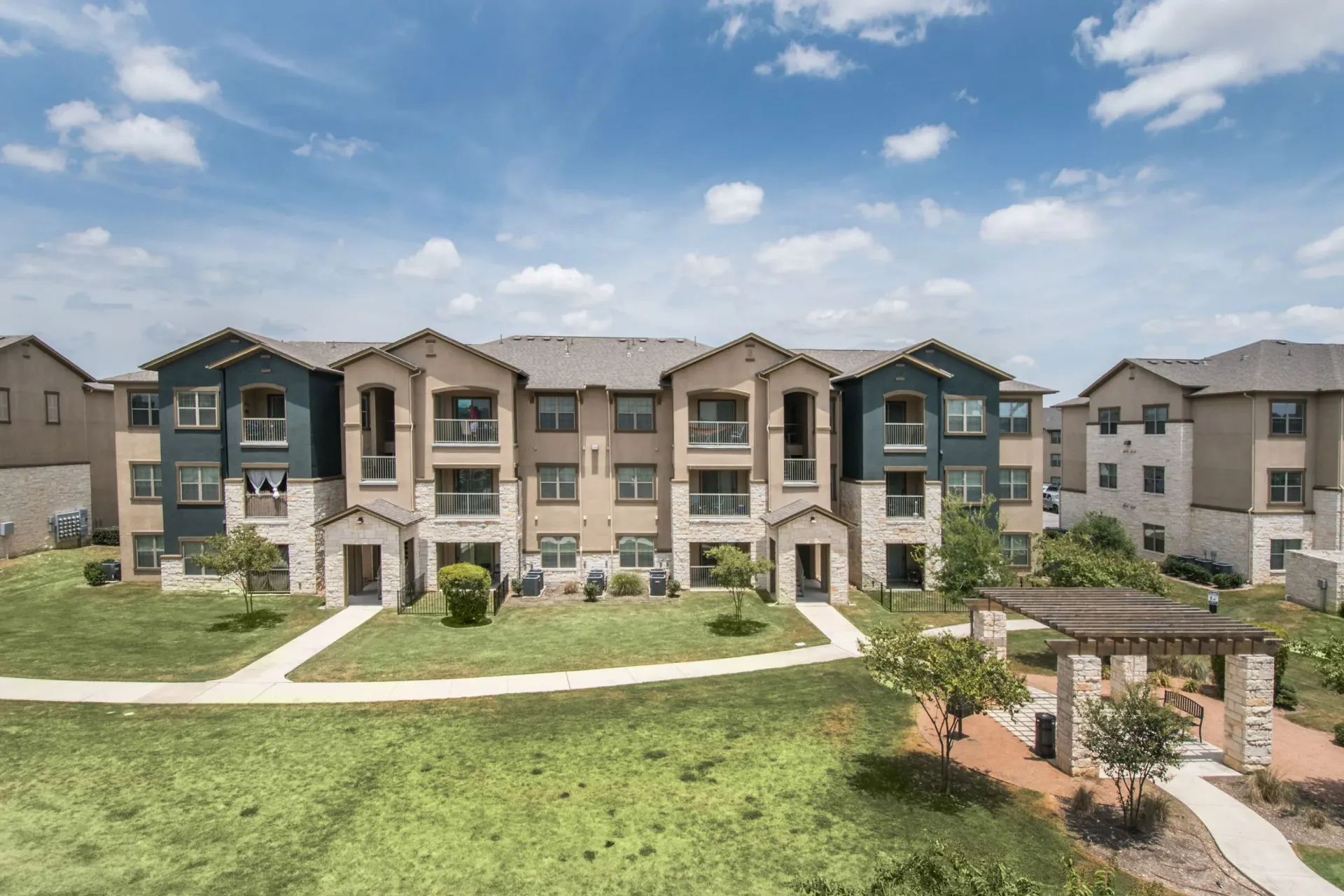Exterior view of a multi-building apartment community with manicured lawn and walkways.