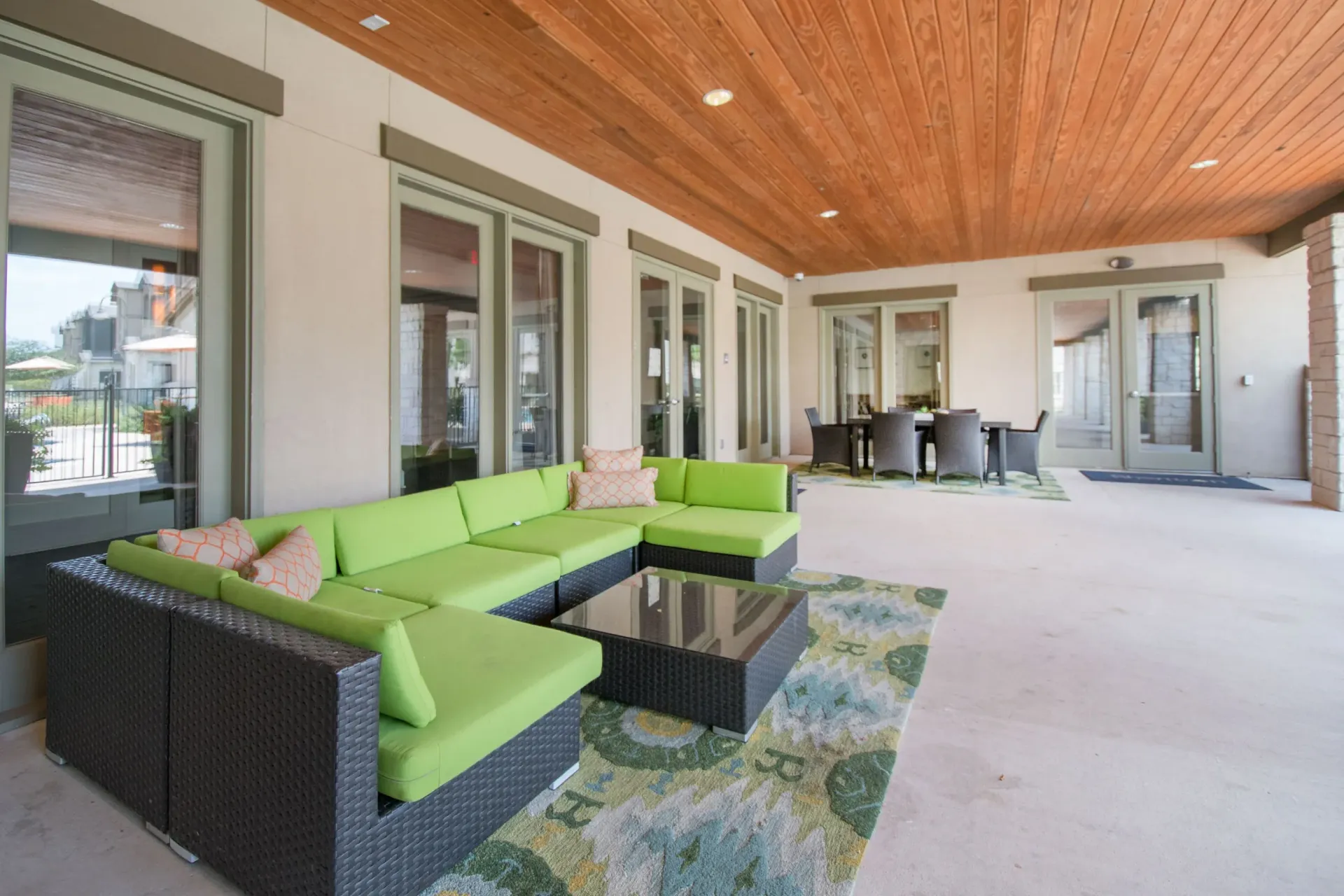 Covered outdoor community lounge with lime-green cushioned sectional and dining table.