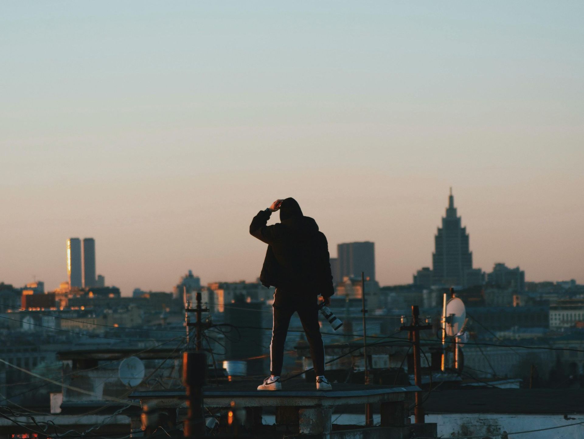 Man standing on rooftop at sunrise overlooking city skyline, symbolizing modern masculinity, inner strength, self-reflection, and emotional resilience